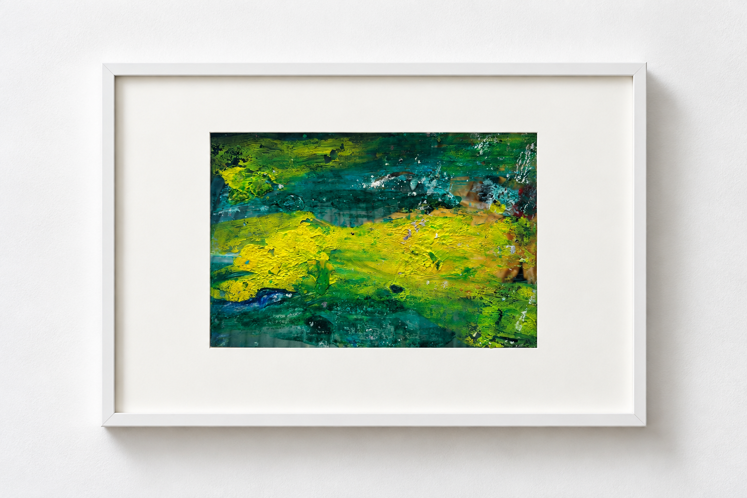 Abstract colorful painting with blue, green, and yellow textures in a white frame on a white wall.