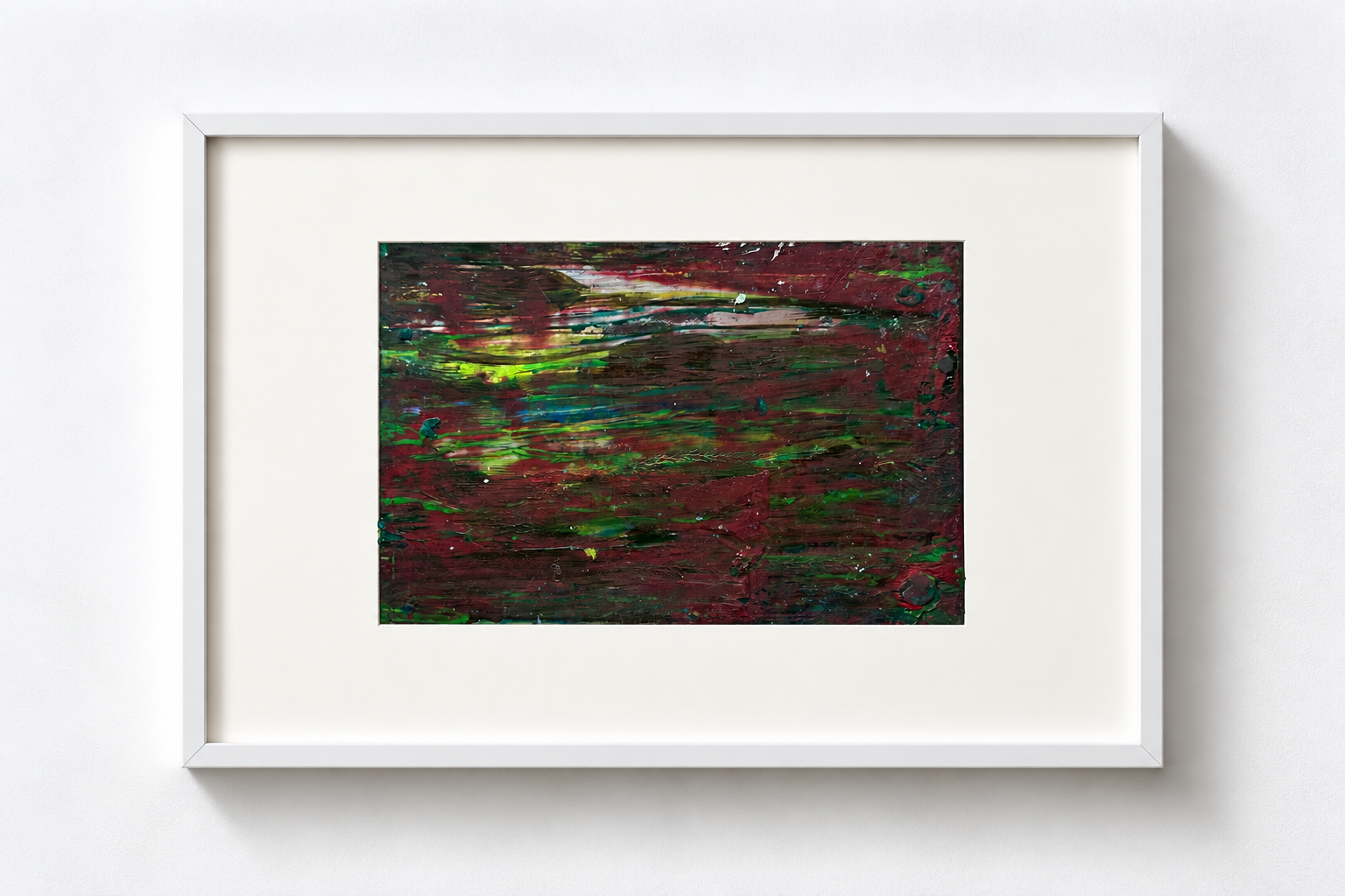 Abstract painting with red, green, yellow, and white brushstrokes, framed and displayed on a white wall.