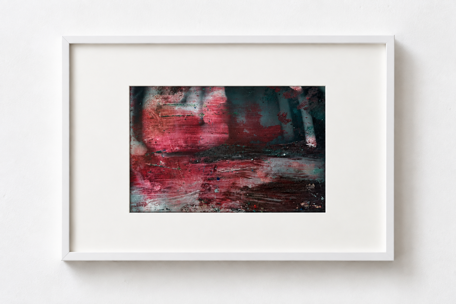 Abstract painting with red, black, and teal colors in a white frame on a white wall.