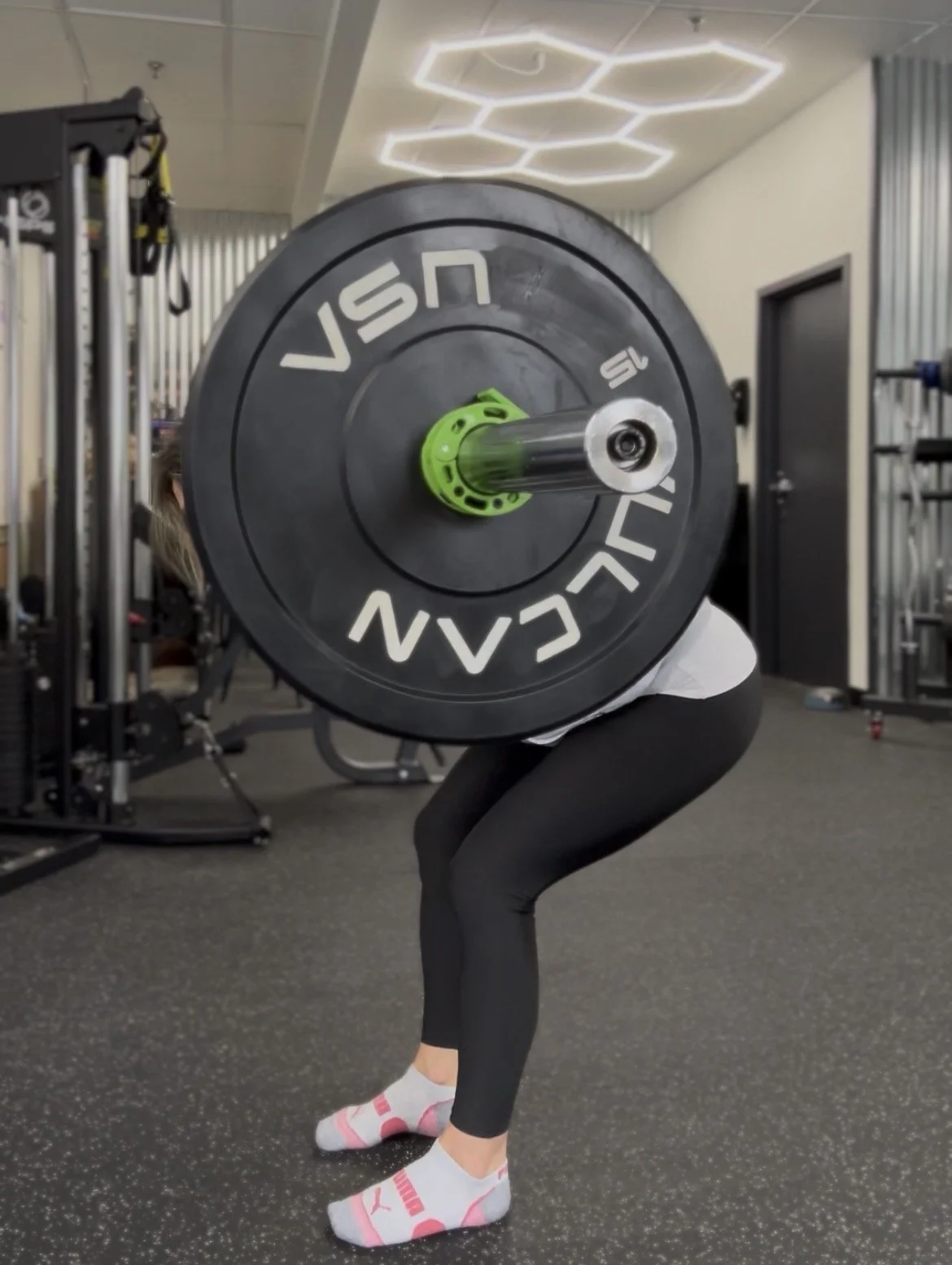 Person performing a barbell squat exercise at the gym.