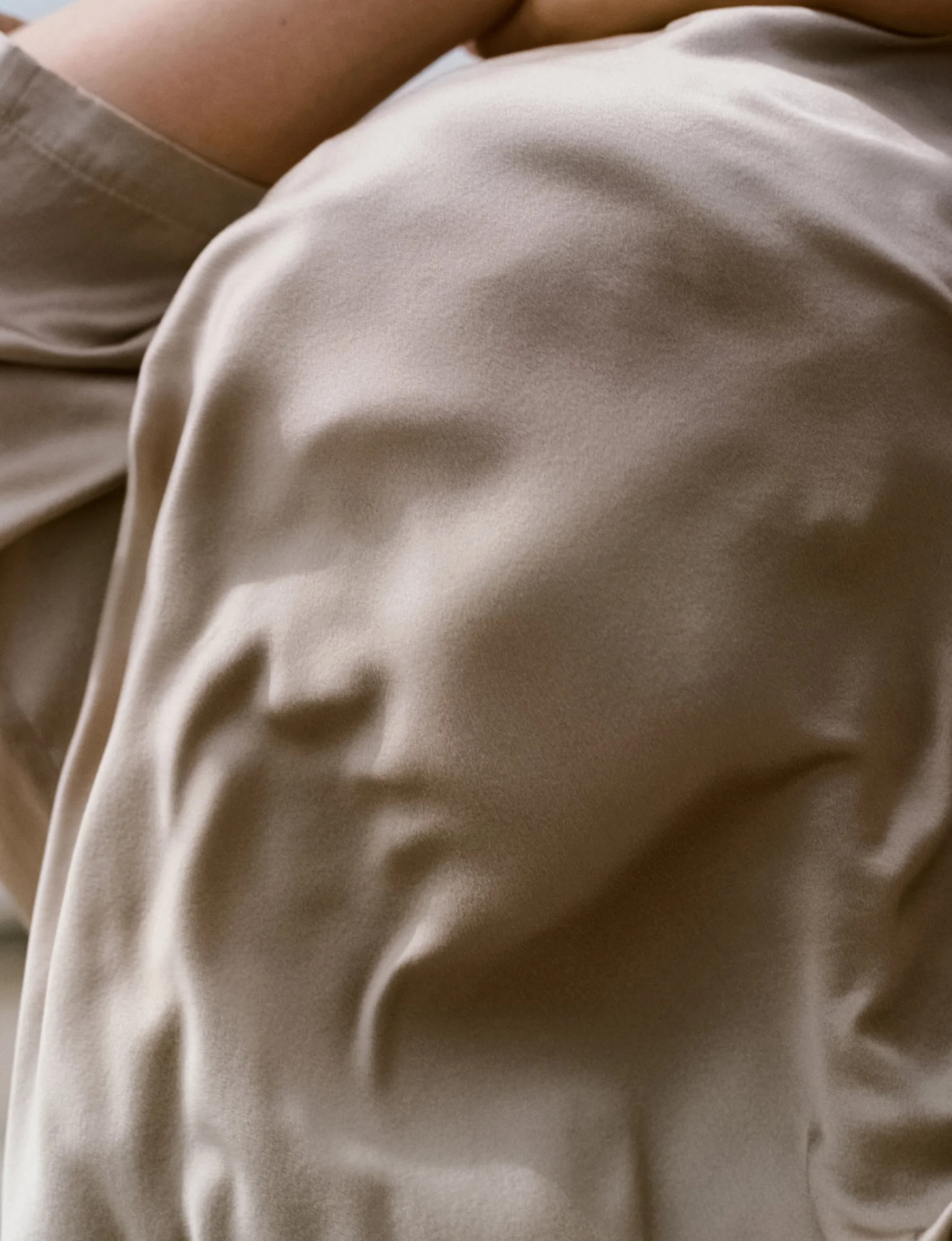 Close-up of beige or cream-colored fabric with visible folds and soft texture.