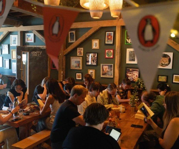 A group of readers sit at benches in a pub.