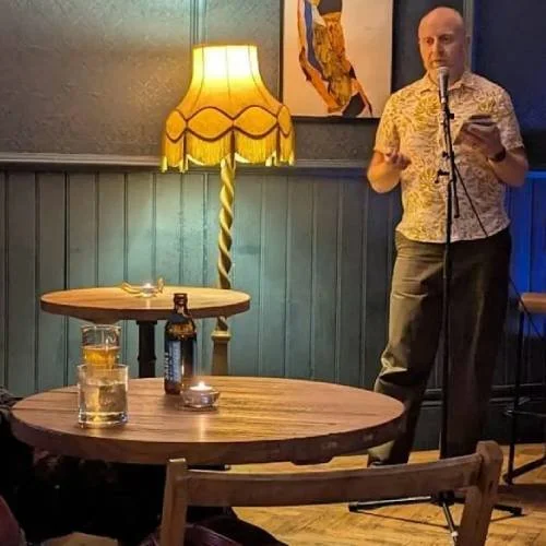 A man stands at a microphone and performs to an audience
