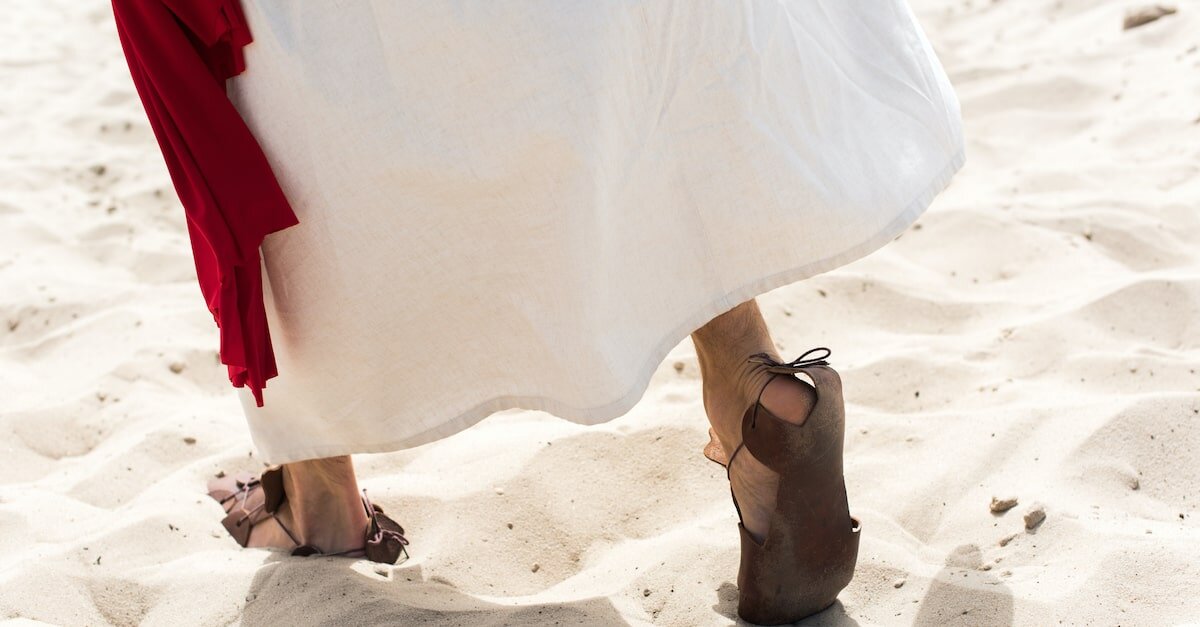 Woman in sandals walks across white sand
