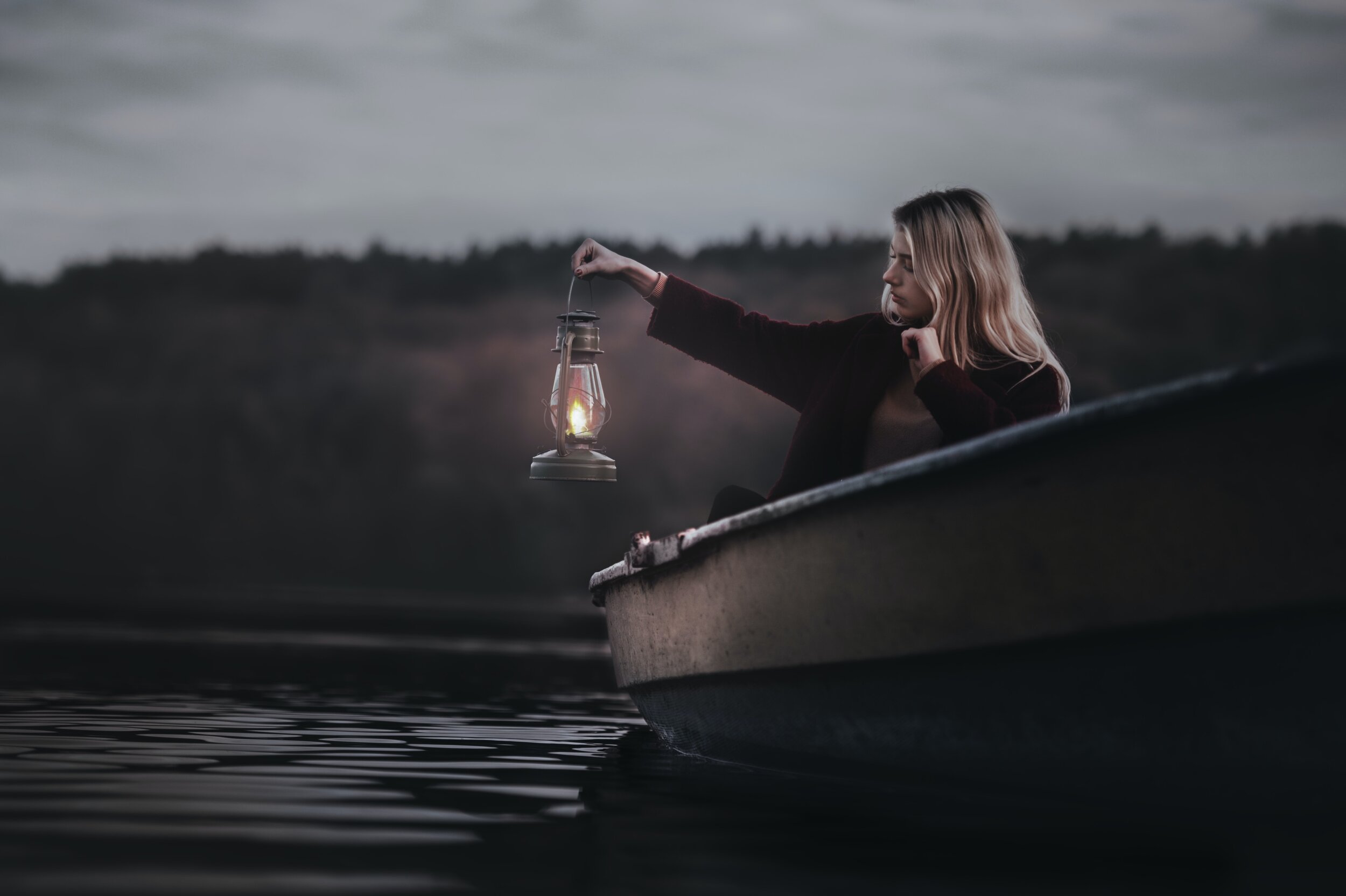 person in boat holding lantern up to see at night