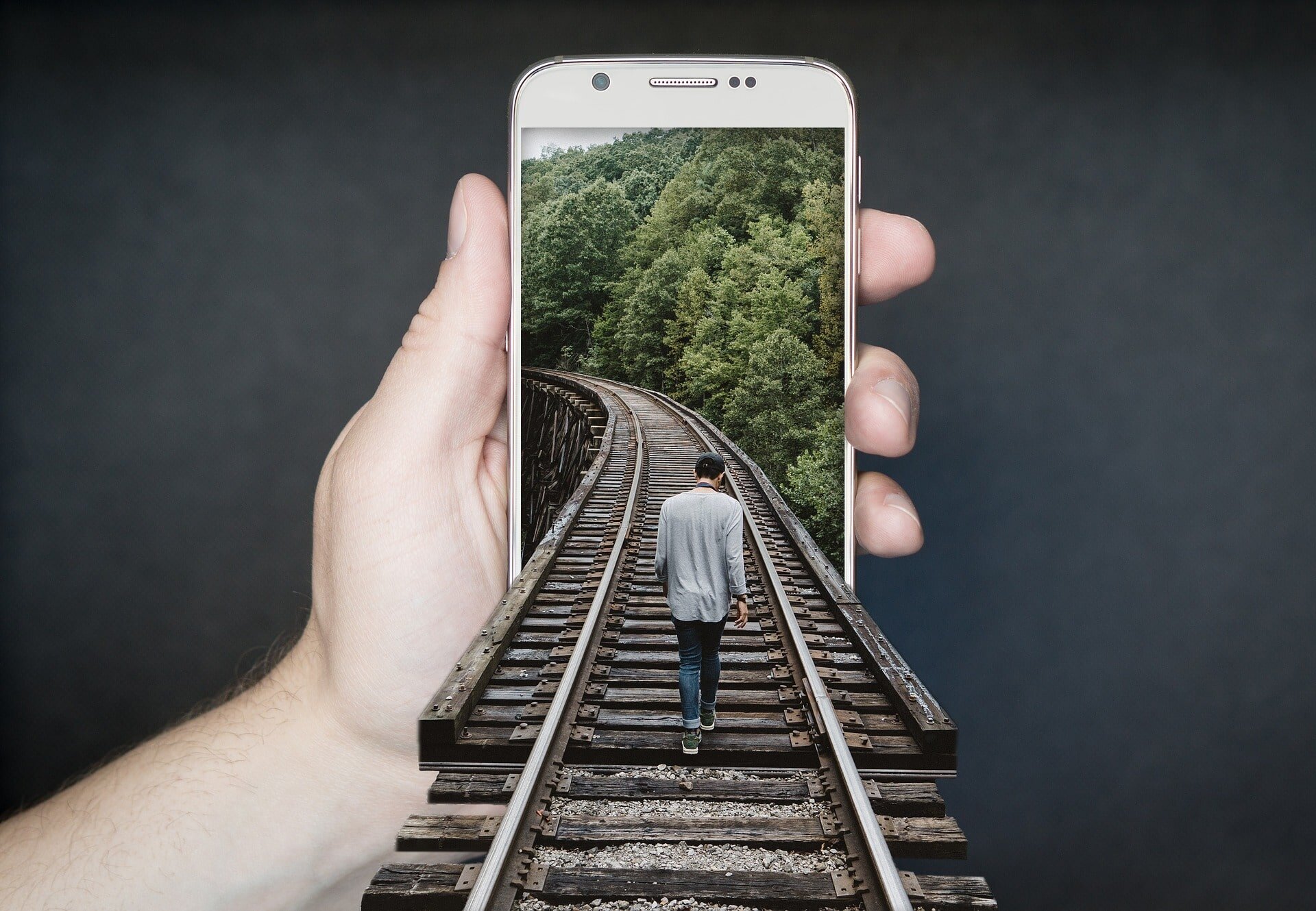 person walking on train tracks superimosed on a smartphone