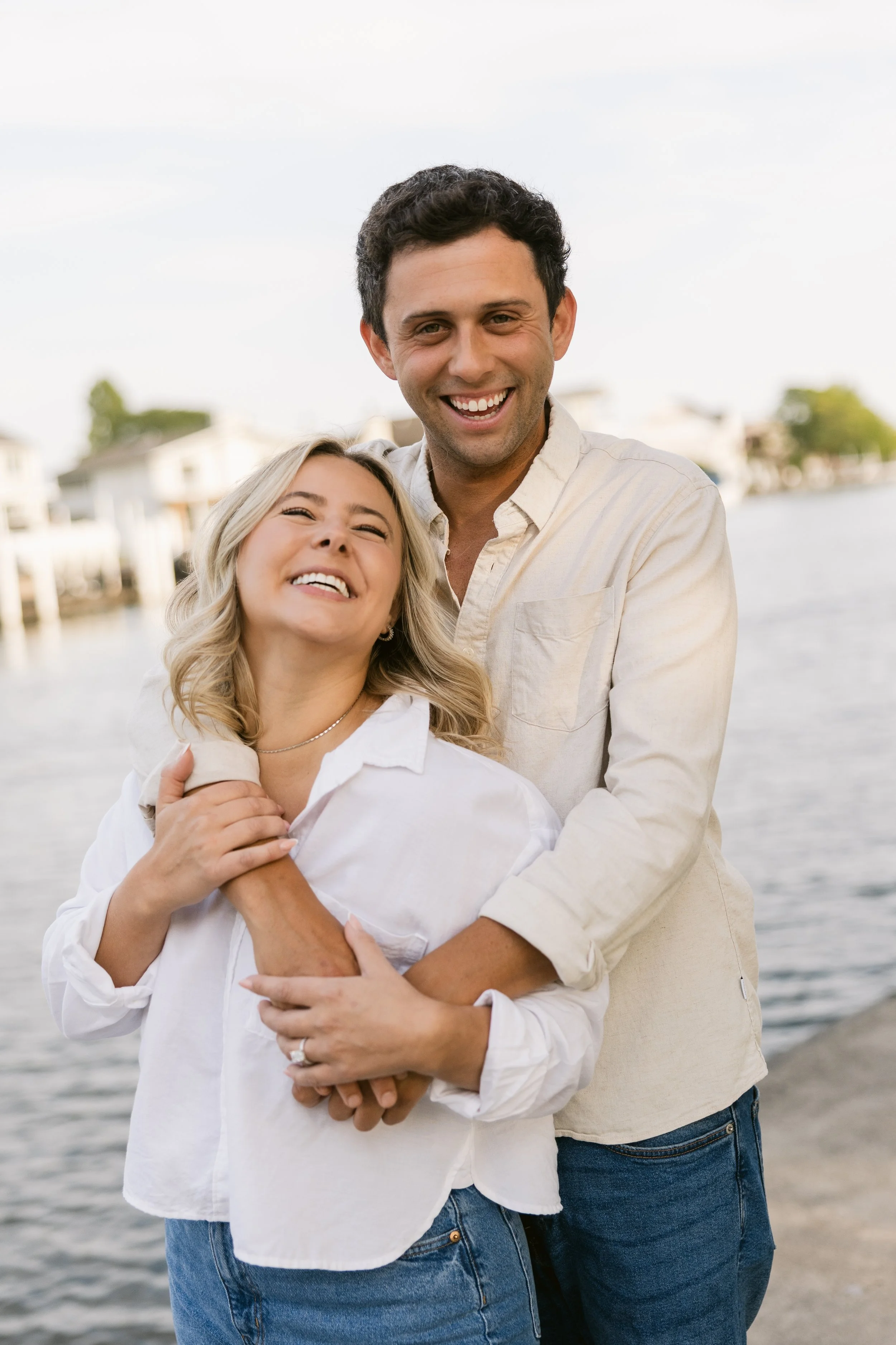 Engaged couple laughing together on a Michigan waterfront