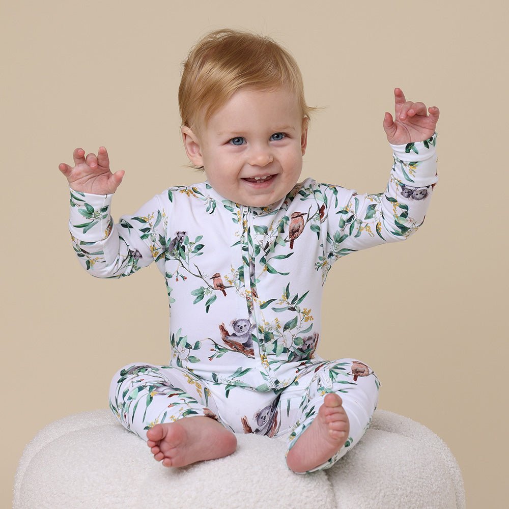 baby wearing an organic cotton onesie. The pattern is koalas and eucalpytus leaves and it has one long zip at the front for easy access.