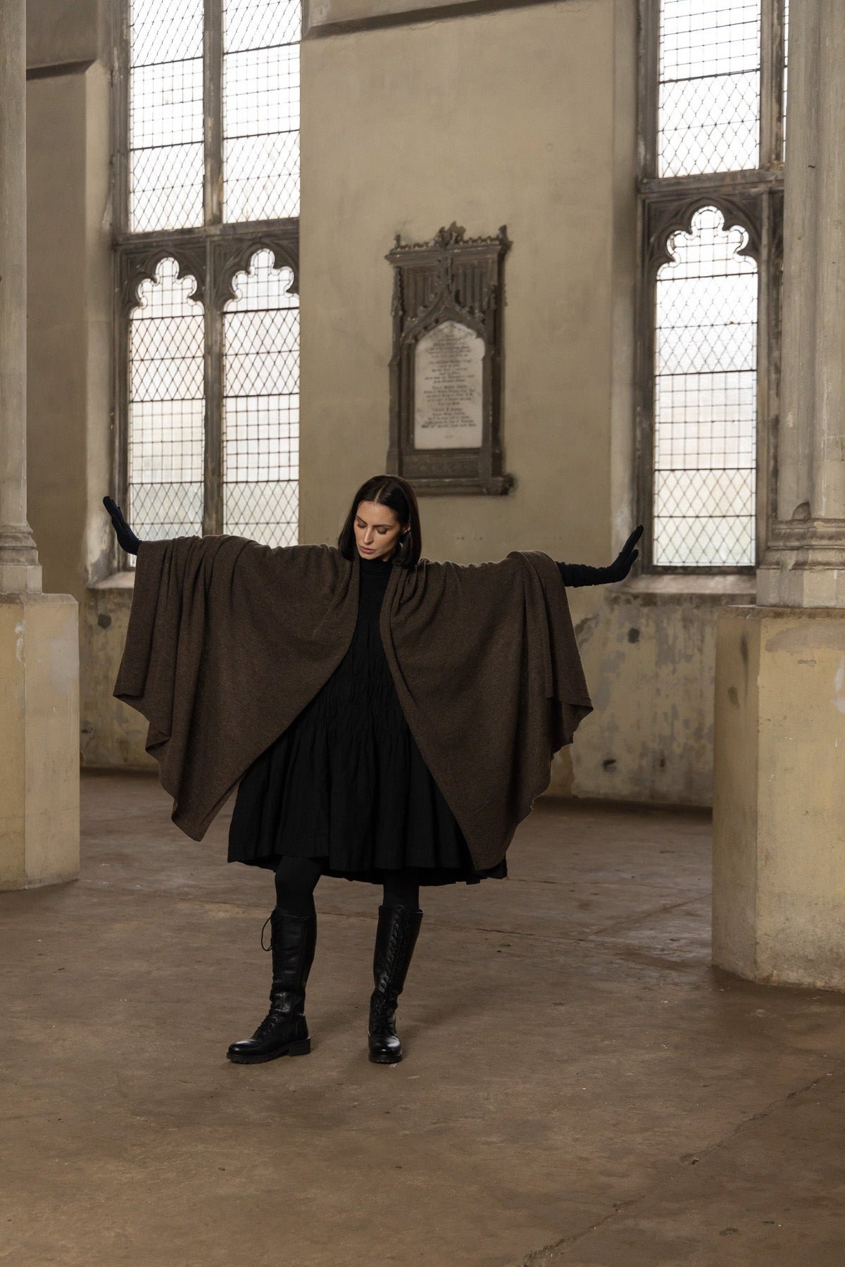 Lady with arms outstretched showing a large chocolate brown woollen shawl.