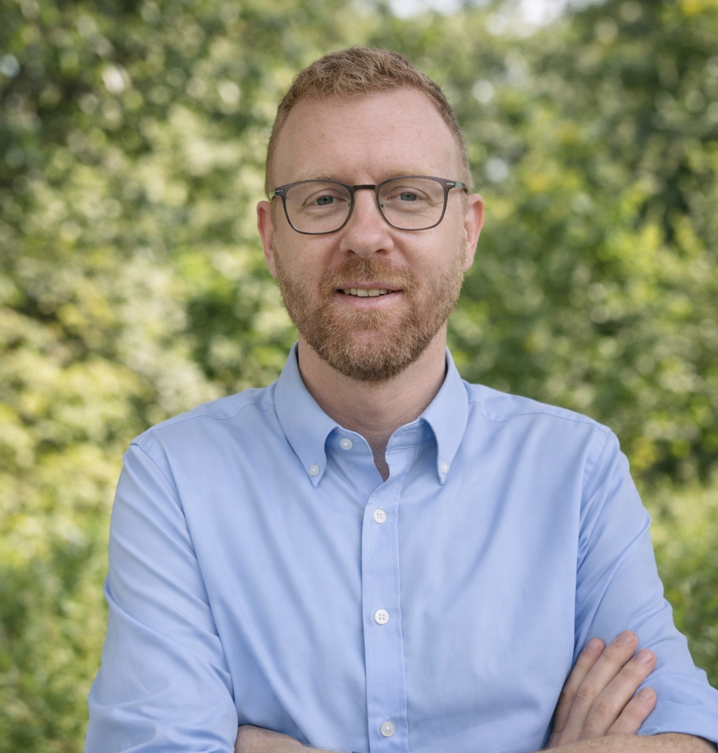 Male with glasses red hair, with a beard smiling into the camera