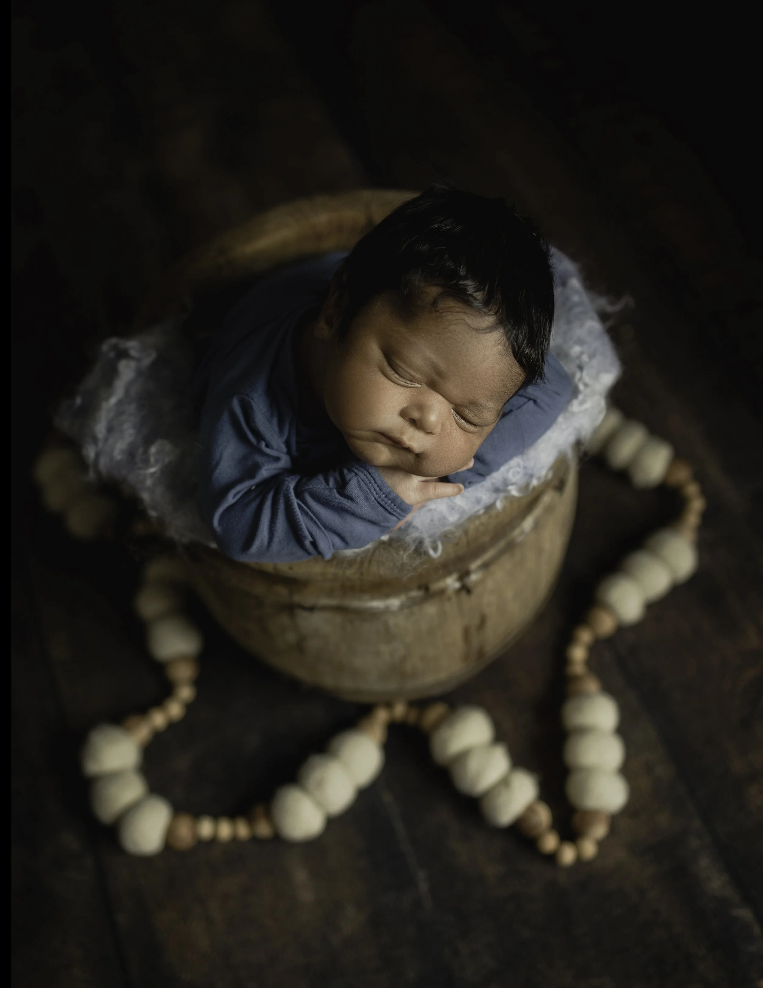 Newborn baby posed in a wooden buscket studio session