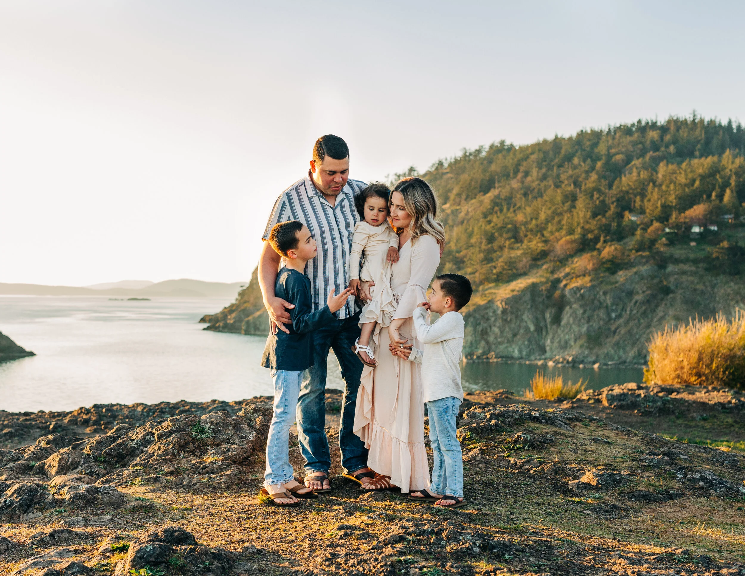 Portrait of family of five hugging on the edge of a cliff from Rosario Beach WA