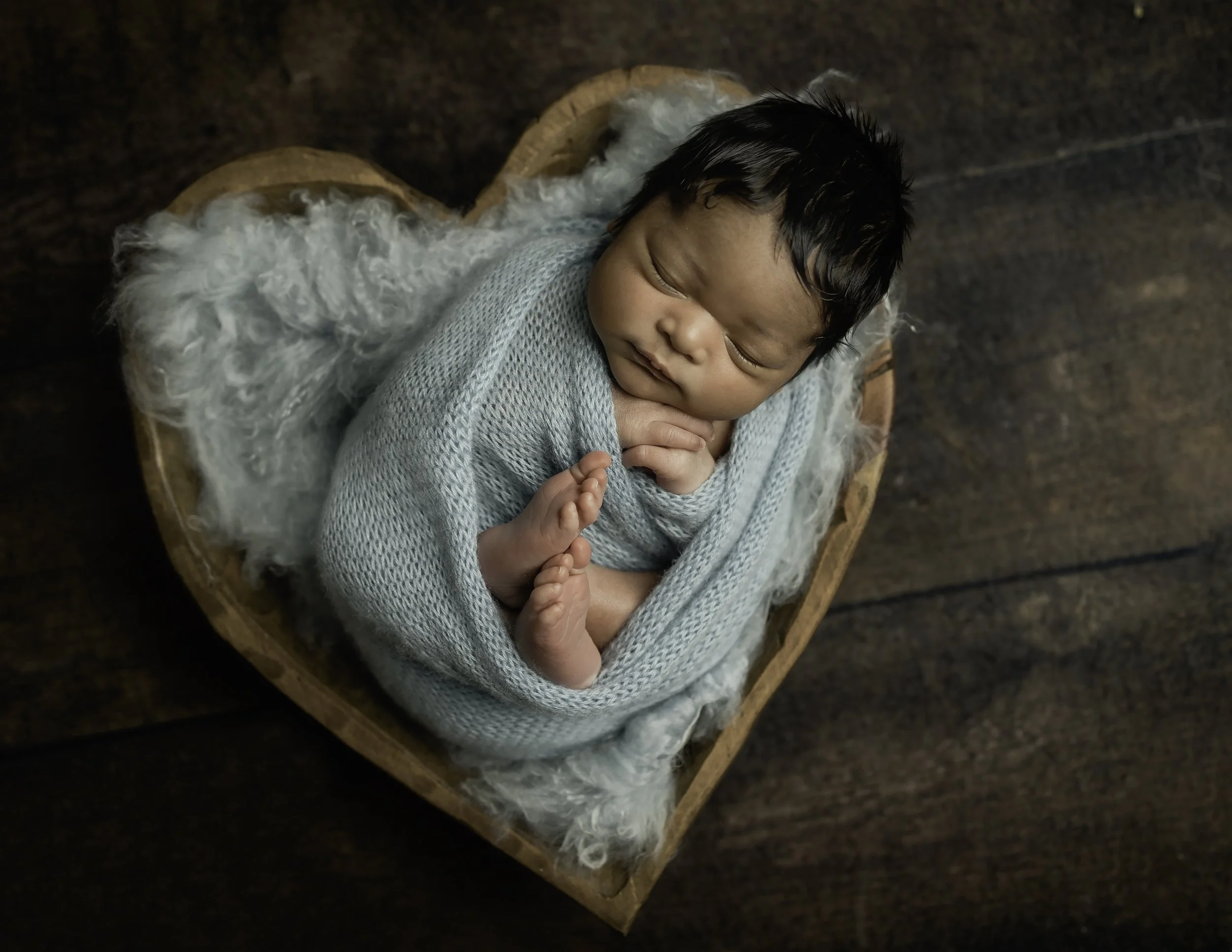 Baby posed in a heart bowl in a studio setting 