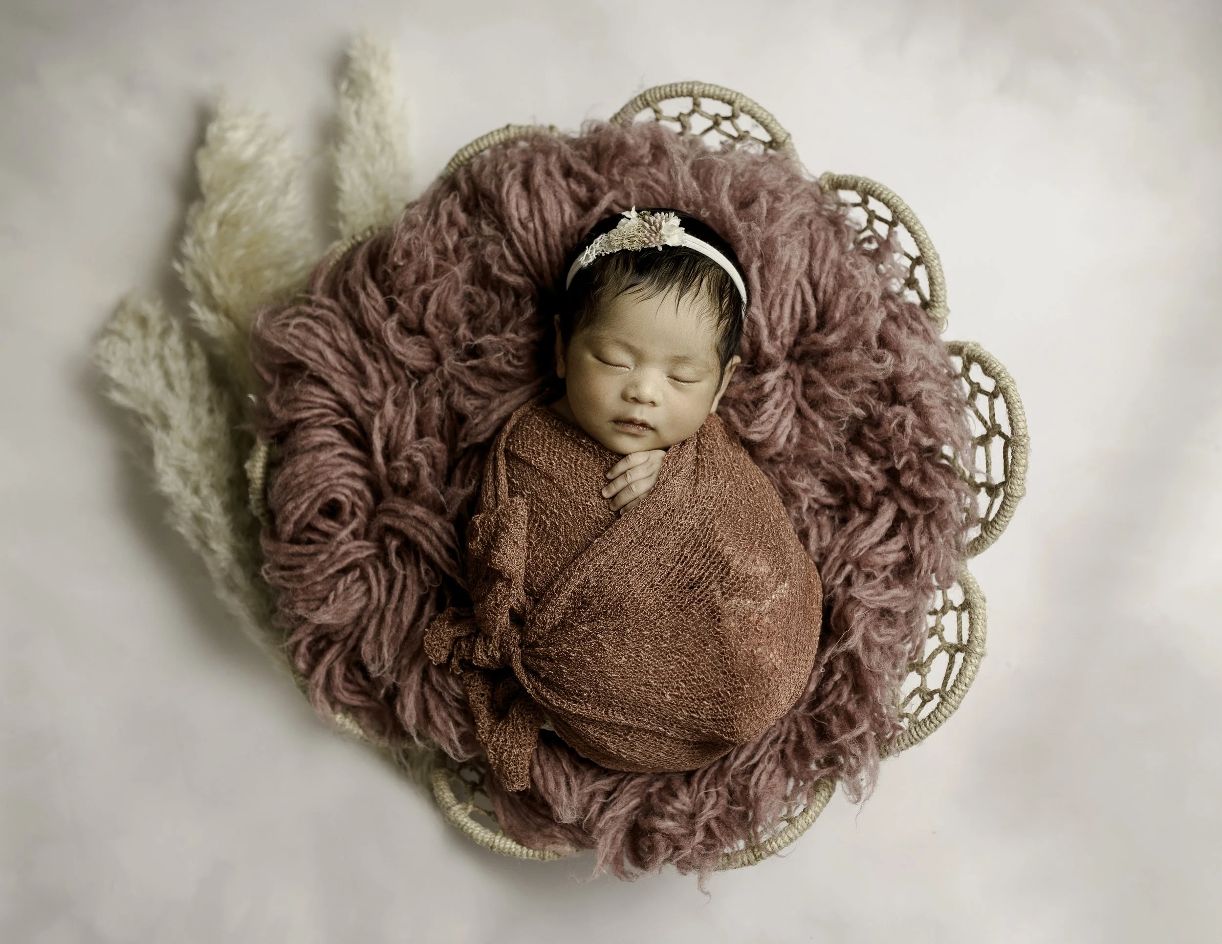 newborn portrait of a baby in a basket with a boho setup