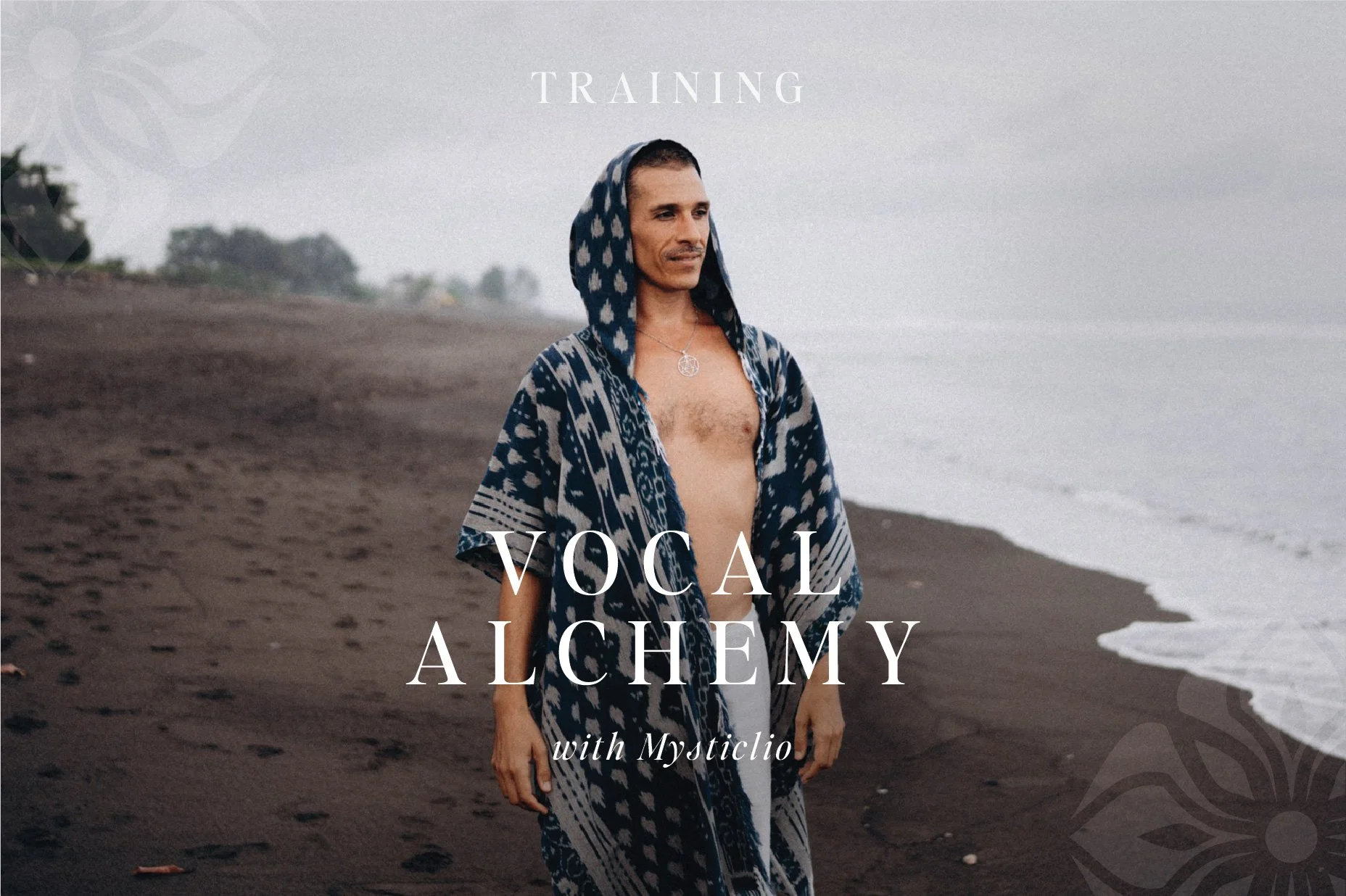 A man with a short haircut stands on a beach, wearing a blue and white patterned hooded robe and a necklace with a circular pendant, looking to the side. The beach has dark sand and the ocean is visible in the background. The sky is overcast. The overlay text reads 'Training Vocal Alchemy with Mysticlio'.