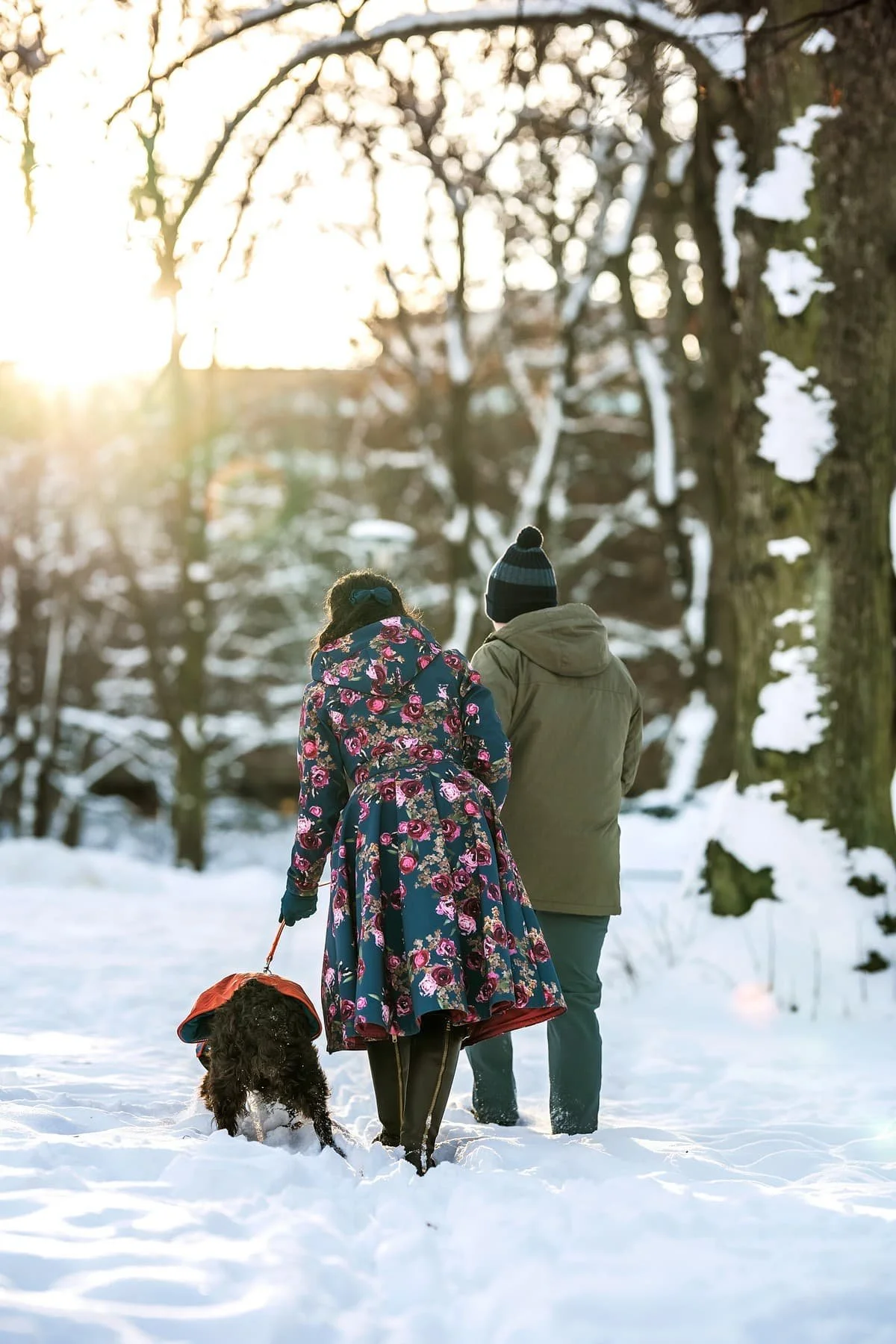 Couple walking in snowy park with dog during end of life photography session in Stockholm