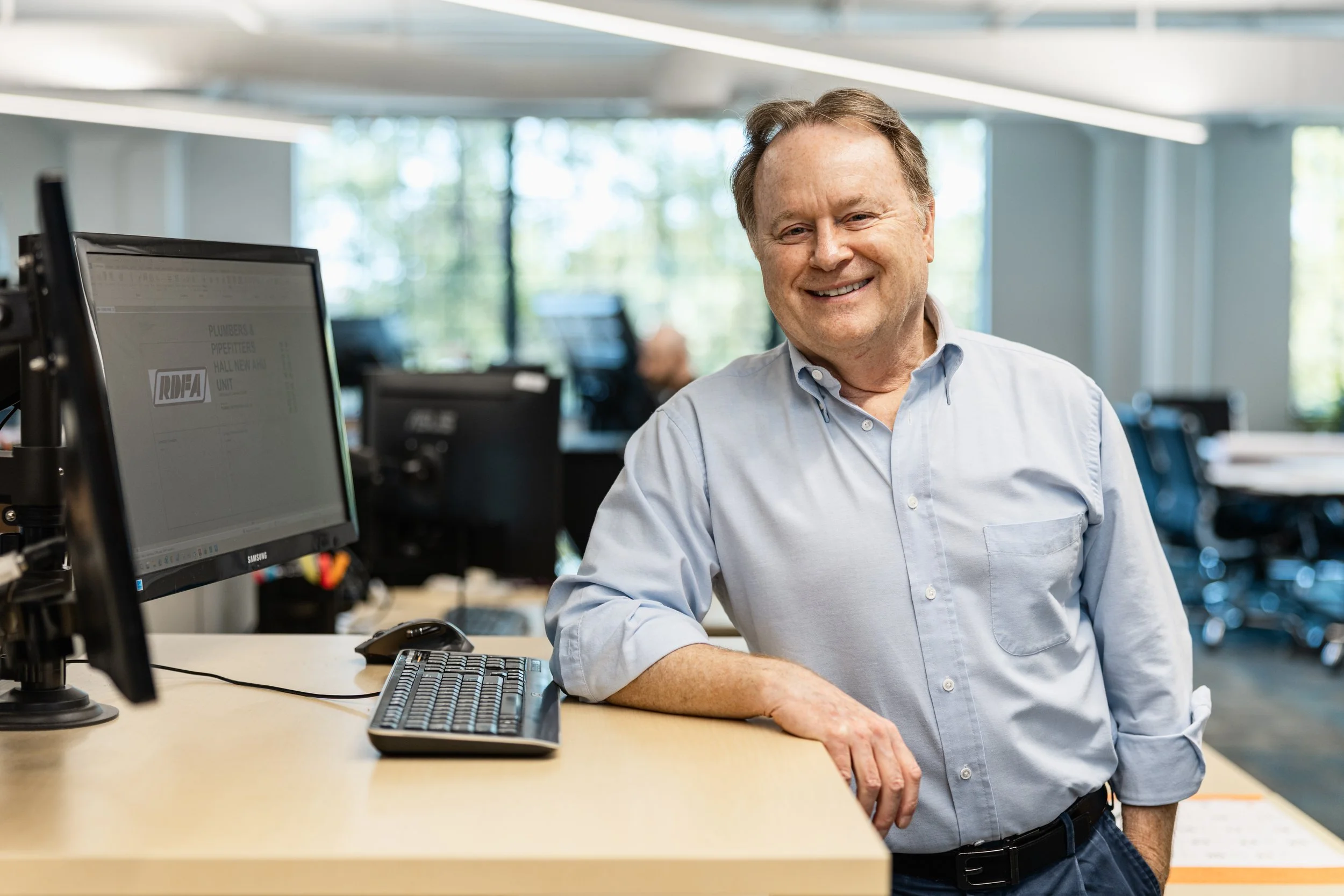 Tod Winters smiling at camera while standing next to his desk