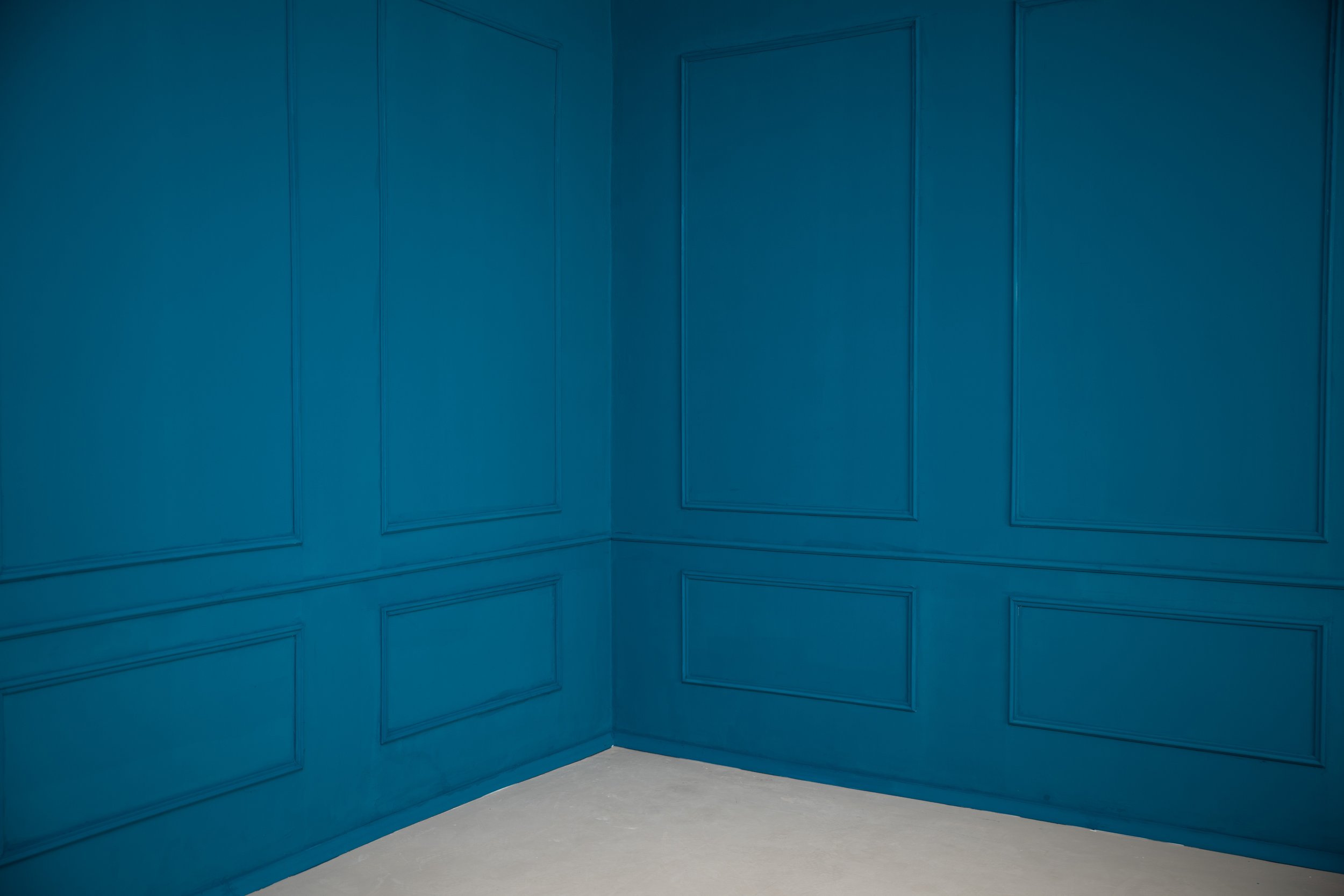 A corner of a room with blue paneled walls and a white floor.