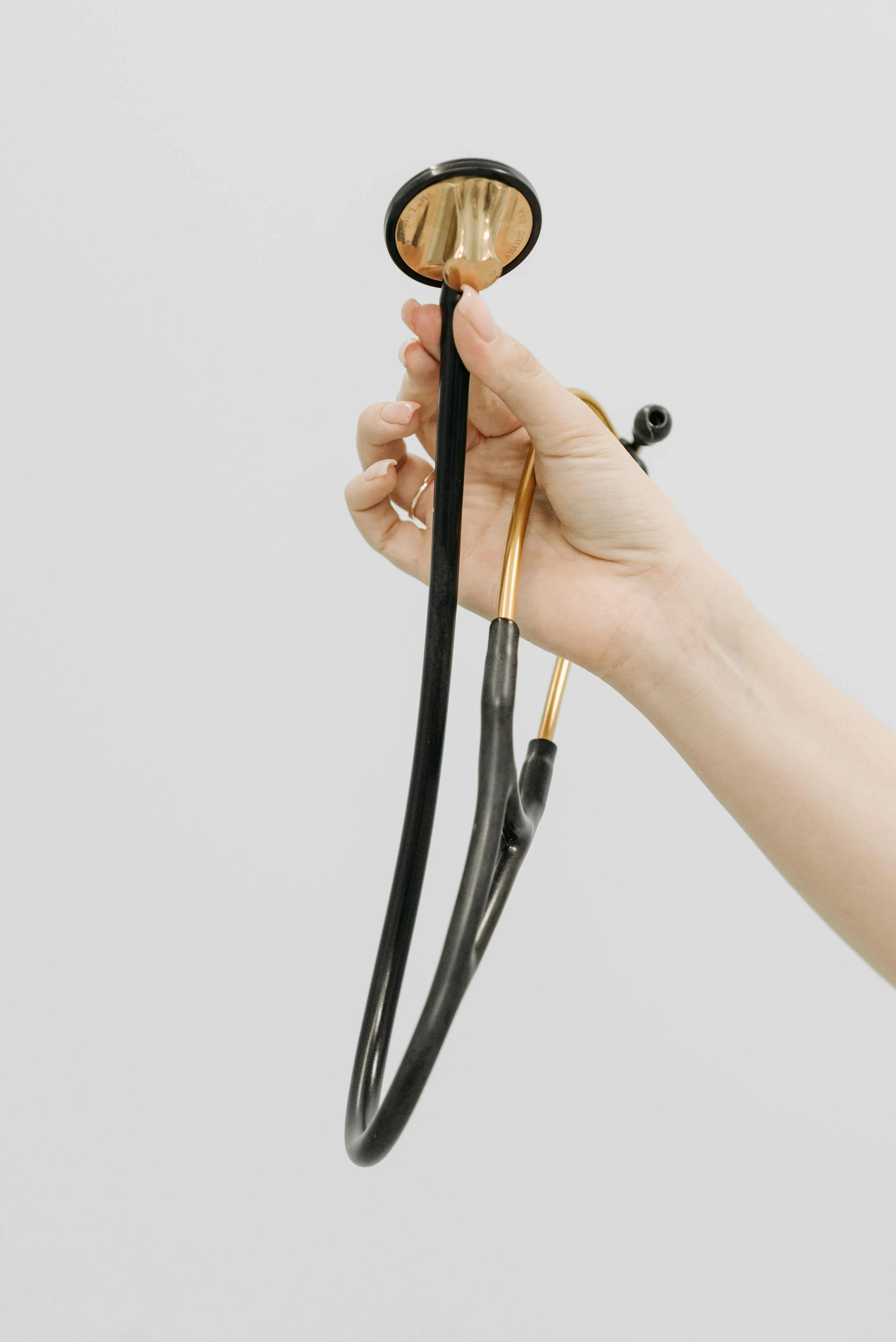 Black and gold stethoscope held in a woman's hand.