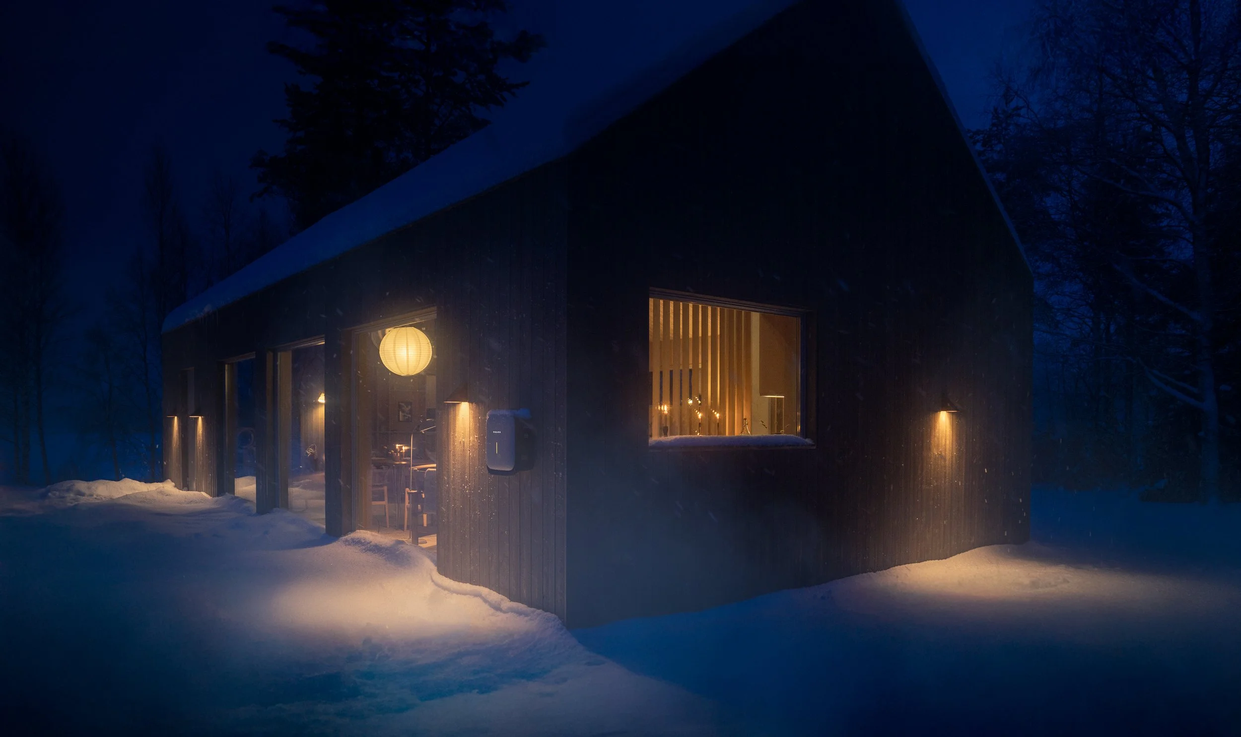 A cozy cabin illuminated from within is surrounded by snow in a wintery forest at night. The cabin has large windows and a paper lantern hangs outside, casting a warm glow.