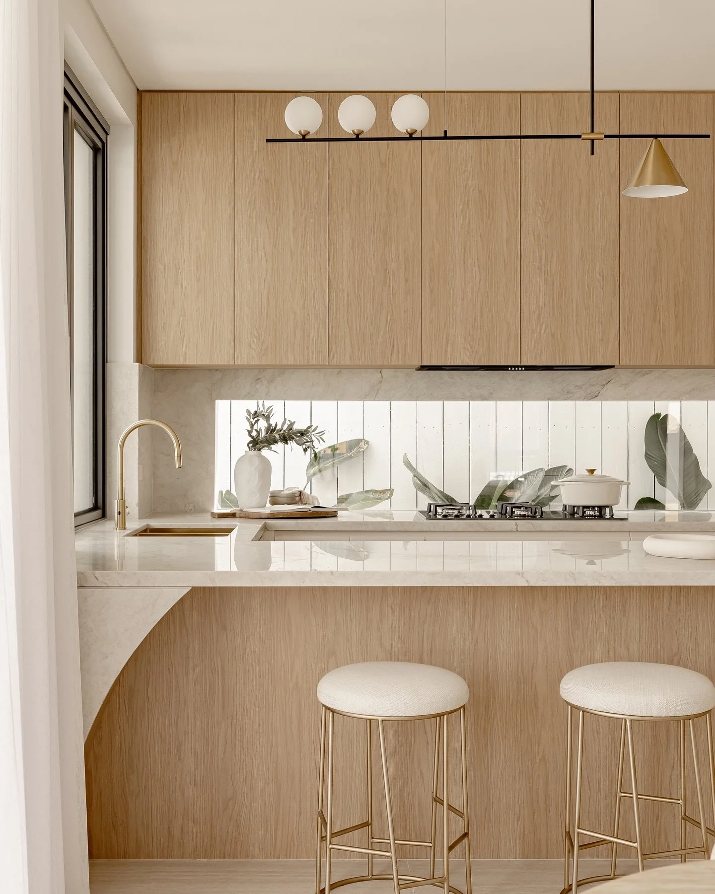 With the window splashback and beautifully landscaped outlook, our team chose a restrained styling approach in this kitchen, ensuring most of the styling accessories were quite low so the view remained the focal point. 
The result? A stunning kitchen