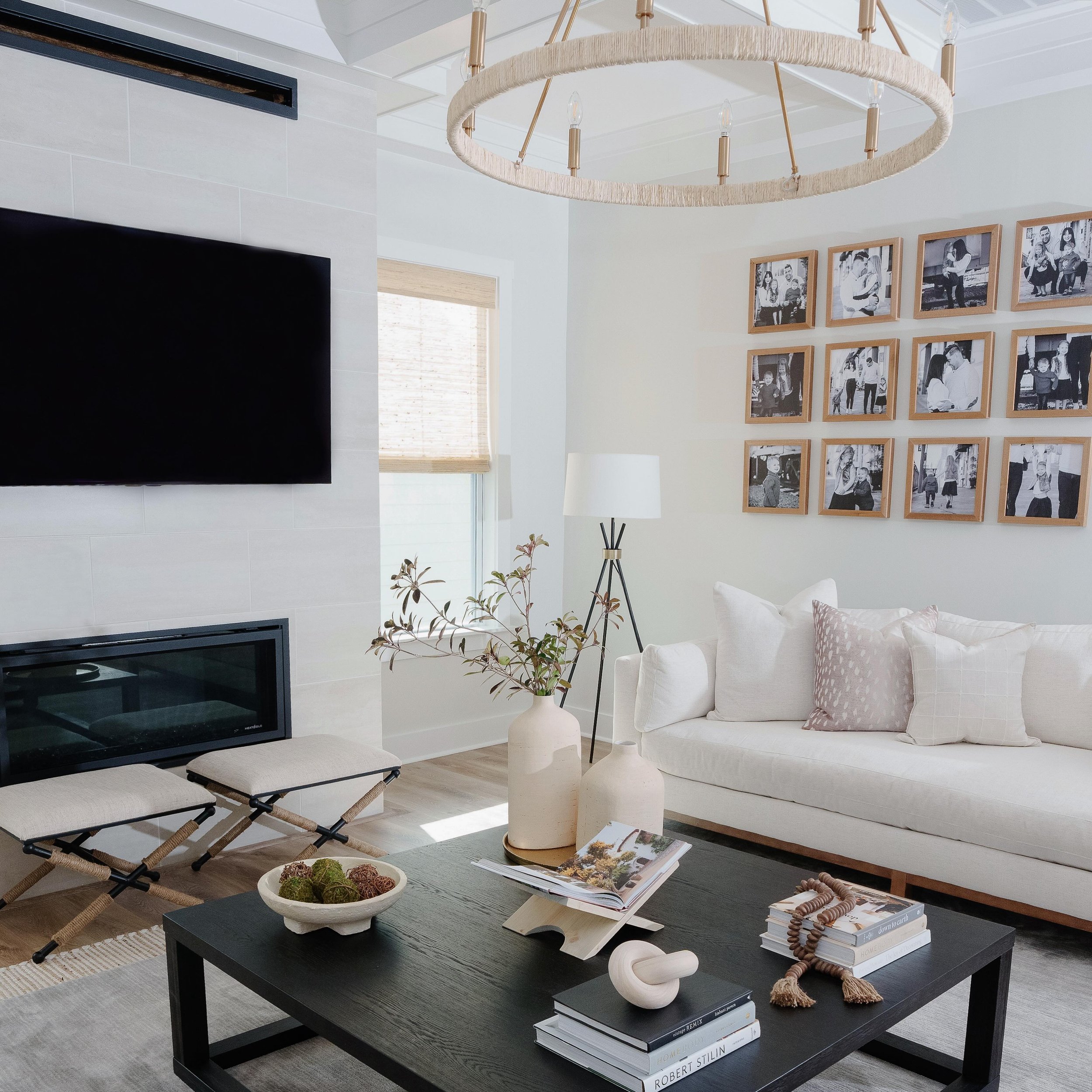 Neutral hues set the tone for relaxation, complemented by a sleek black coffee table and the timeless elegance of a traditional chandelier wrapped in rope for a modern touch. 🖤