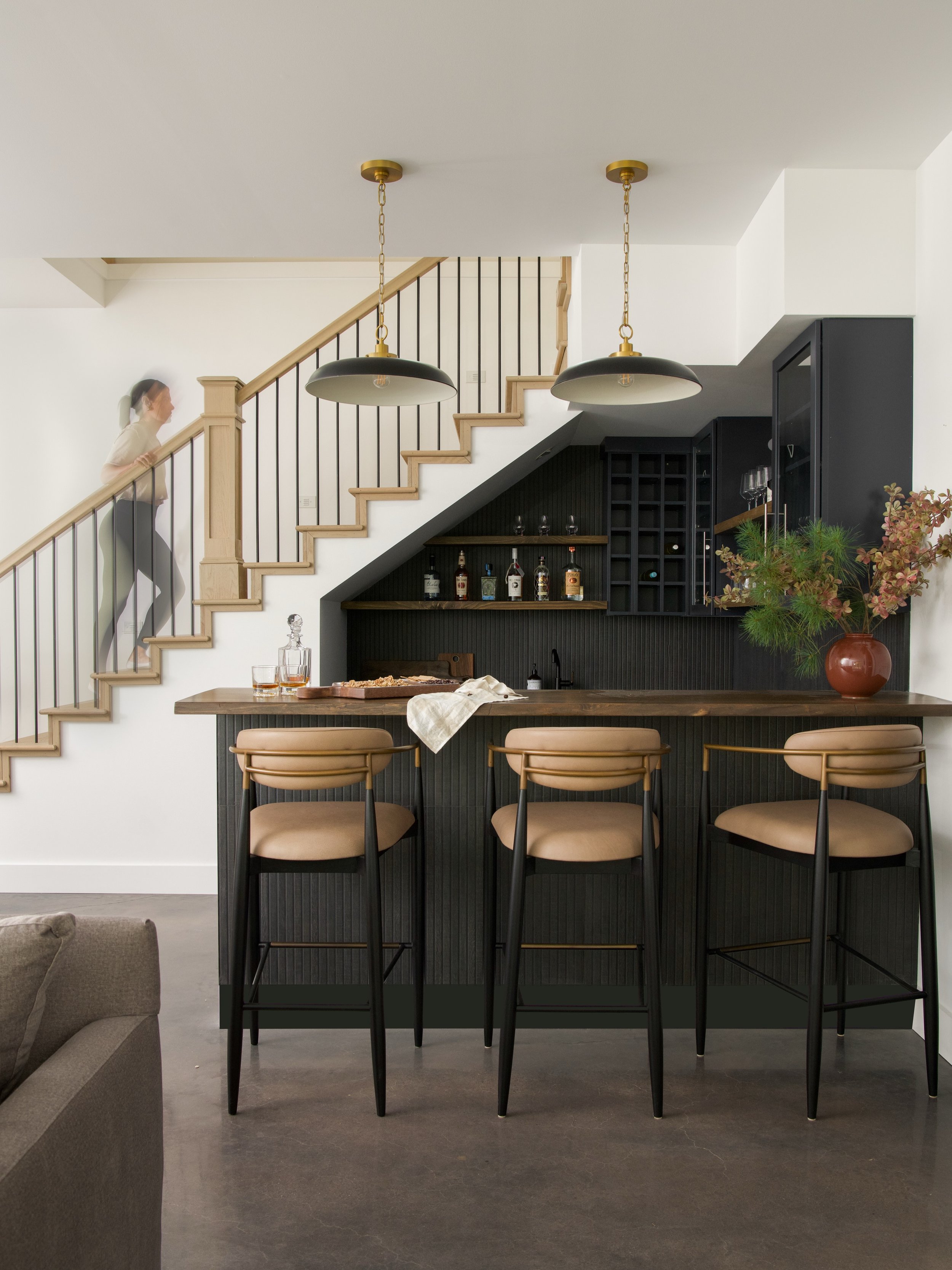 The space under the stairs is often an afterthought. Here, it became the best seat in the house. 

We tucked a full moody bar into what used to be dead space - fluted paneling, a walnut top, and just enough brass magic
 to make it feel like a proper 
