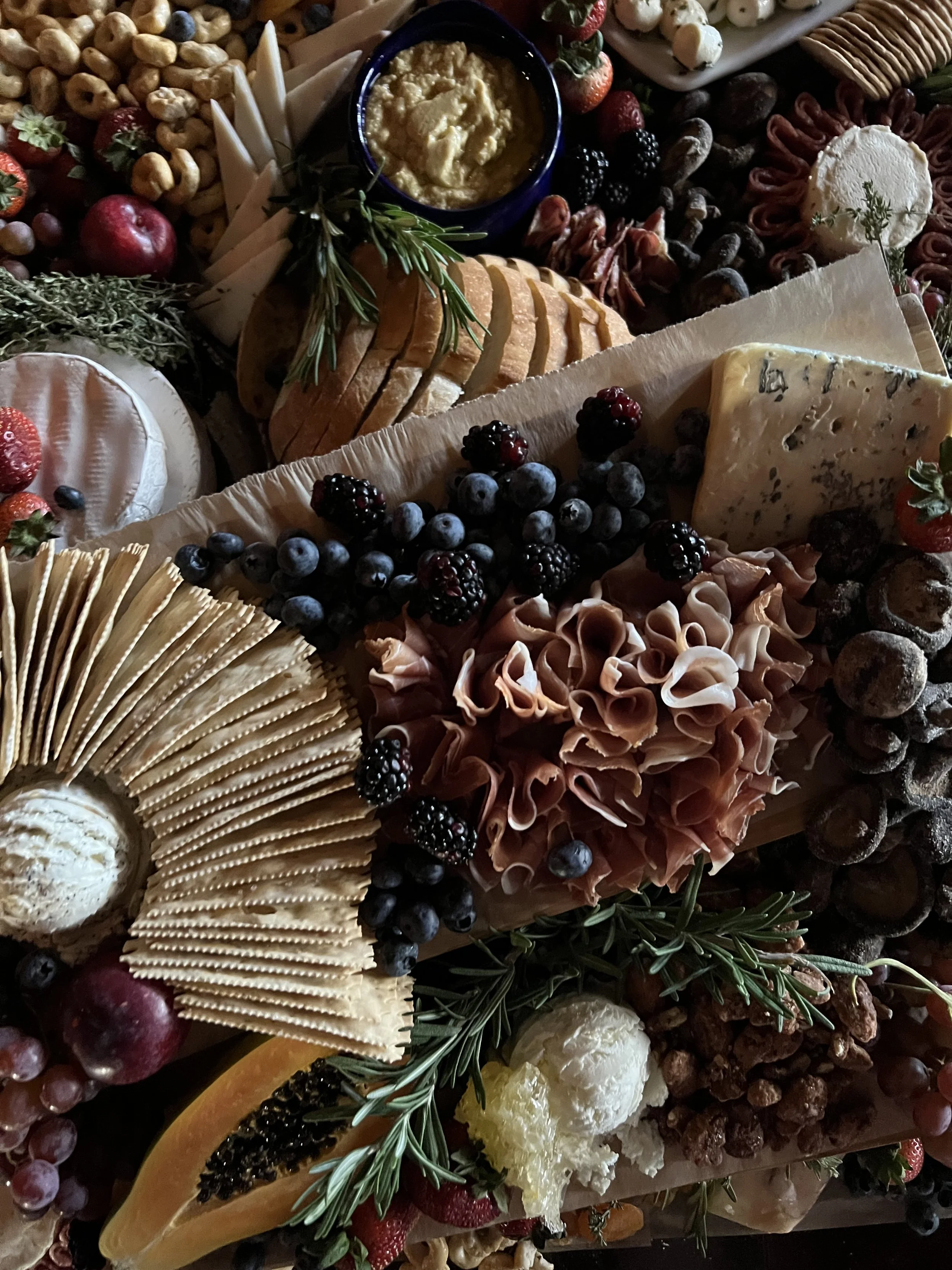 Charcuterie board with meats, cheeses, crackers, fruits, and nuts.