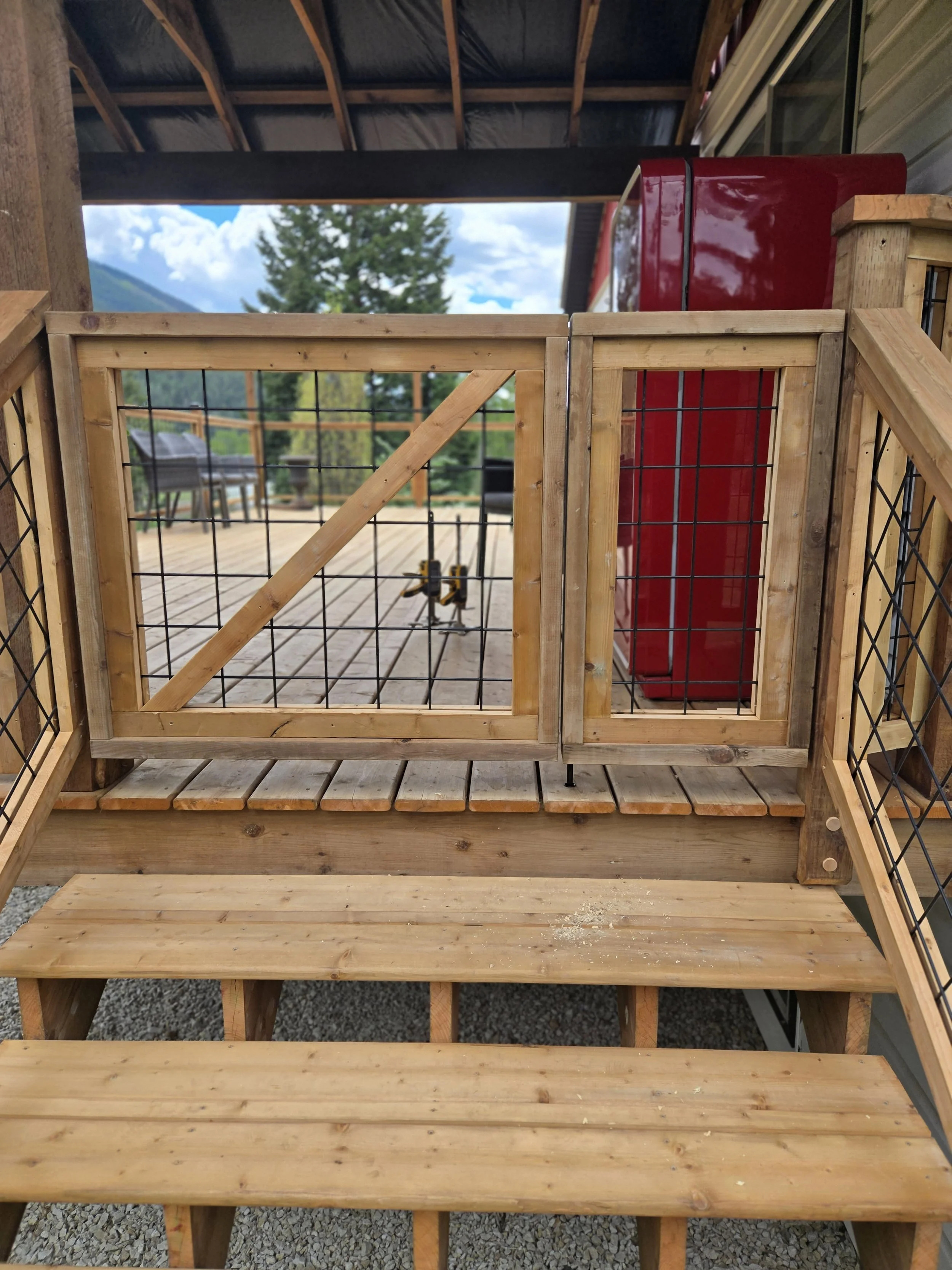 Wooden deck with railing, red refrigerator, and mountain scenery in the background.