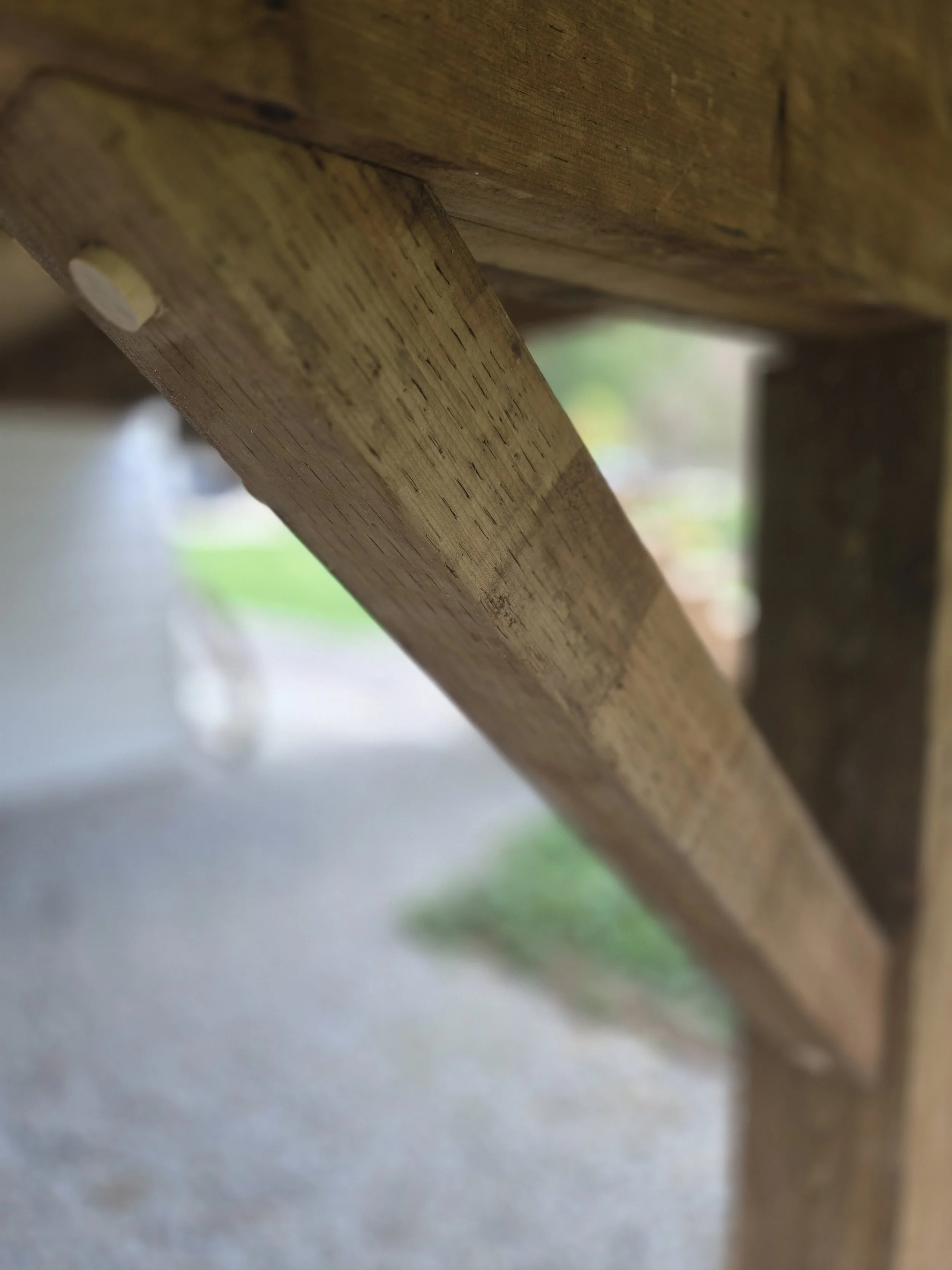 Close-up of a wooden table leg attached with a bolt, showing the wood grain and texture.
