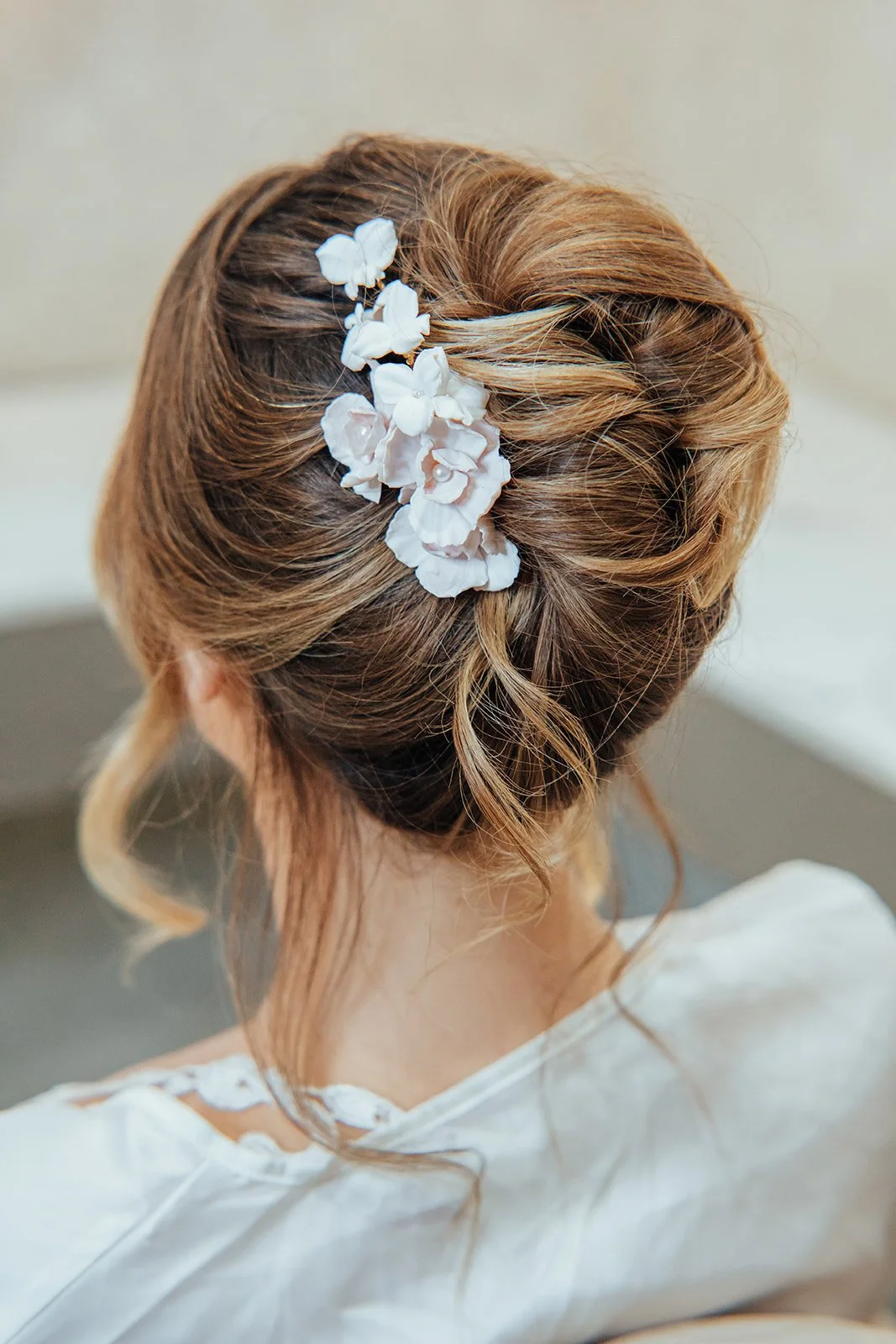 Cherry Blossom and Trillium bridal hairpiece in pale pink and white with pearl accents, styled on a sleek updo for weddings.