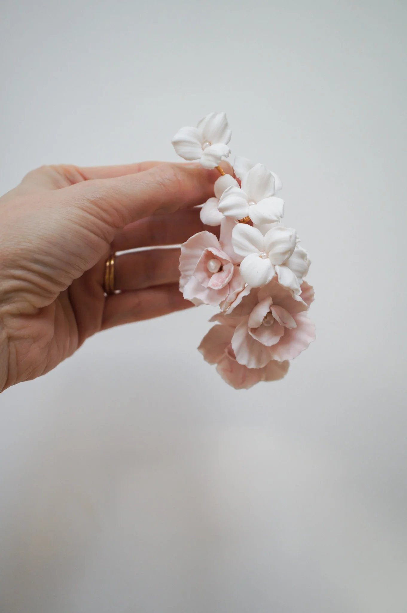 Cherry Blossom and Trillium bridal hairpiece in pale pink and white with pearl accents, styled for a sleek updo for weddings.