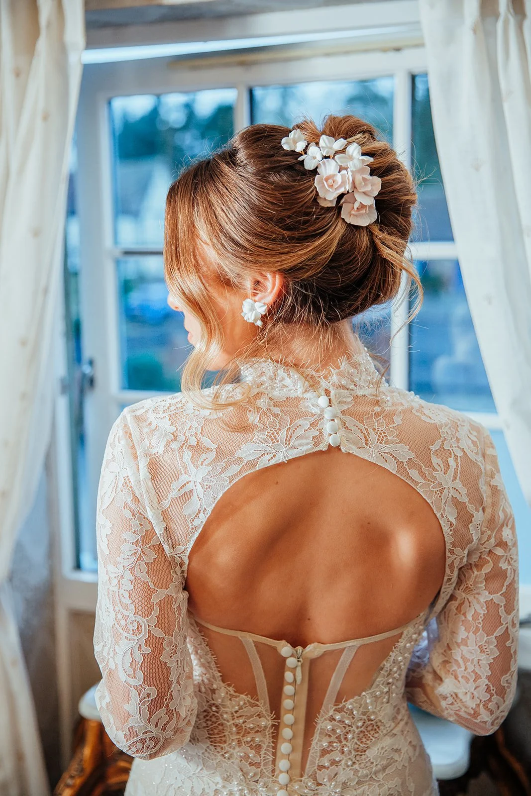Cherry Blossom and Trillium bridal hairpiece in pale pink and white with pearl accents, styled on a sleek updo for weddings.