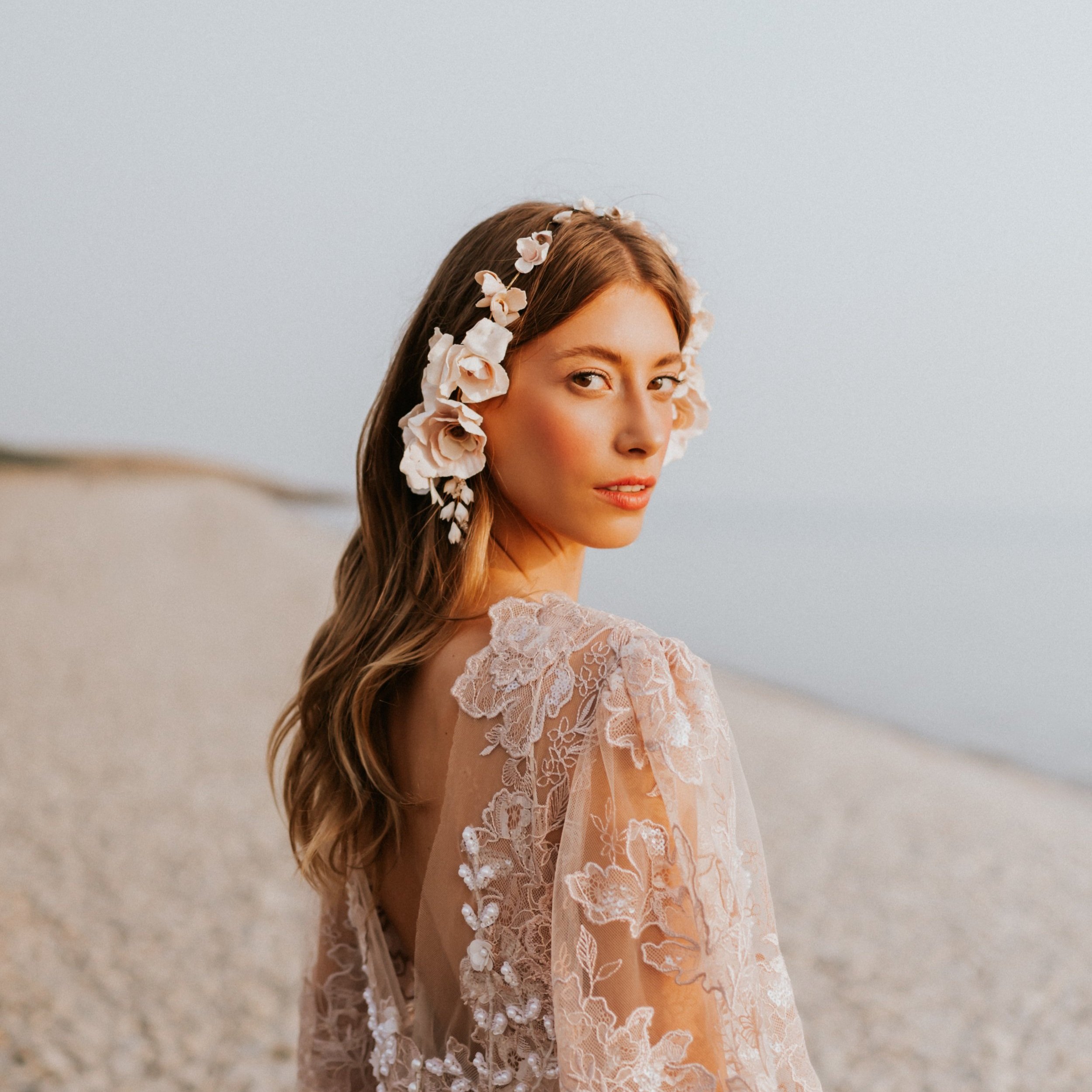 Close-up of a handmade clay flower hairvine in pale pink on both sides of the head, showcasing delicate, realistic petal textures and fine craftsmanship.