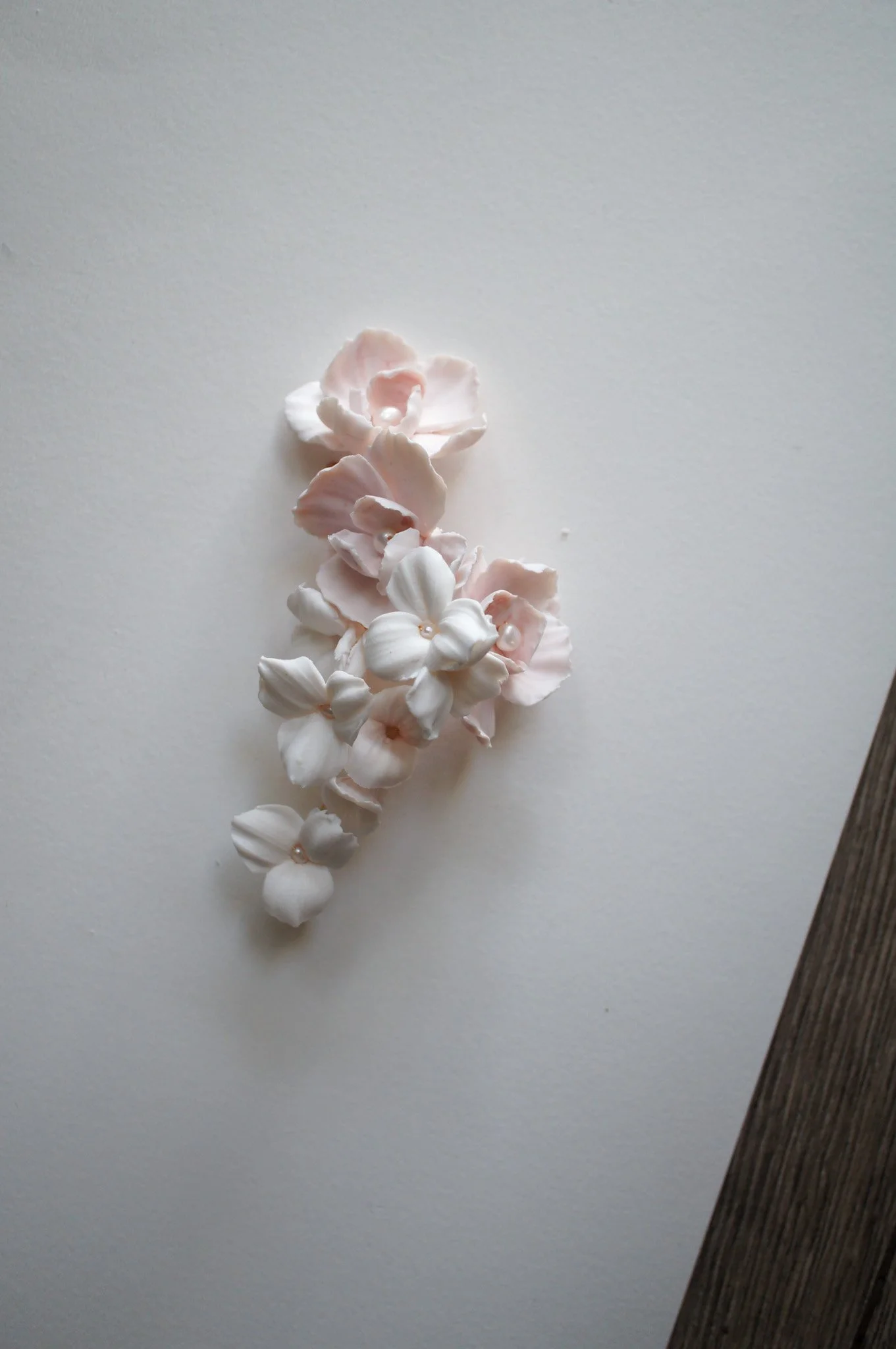 Cherry Blossom and Trillium bridal hairpiece in pale pink and white with pearl accents, styled for a sleek updo for weddings.