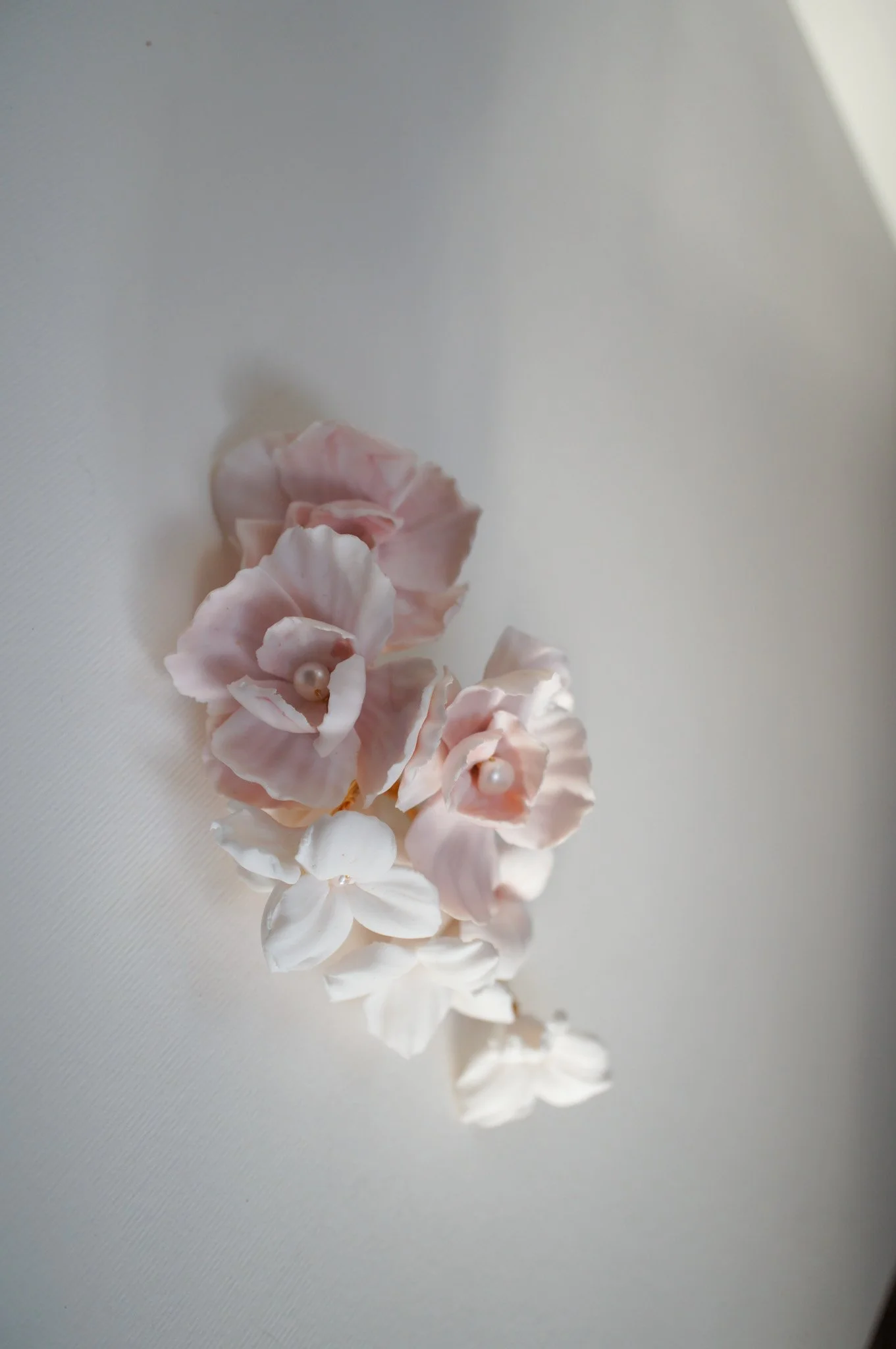 Cherry Blossom and Trillium bridal hairpiece in pale pink and white with pearl accents, styled for a sleek updo for weddings.