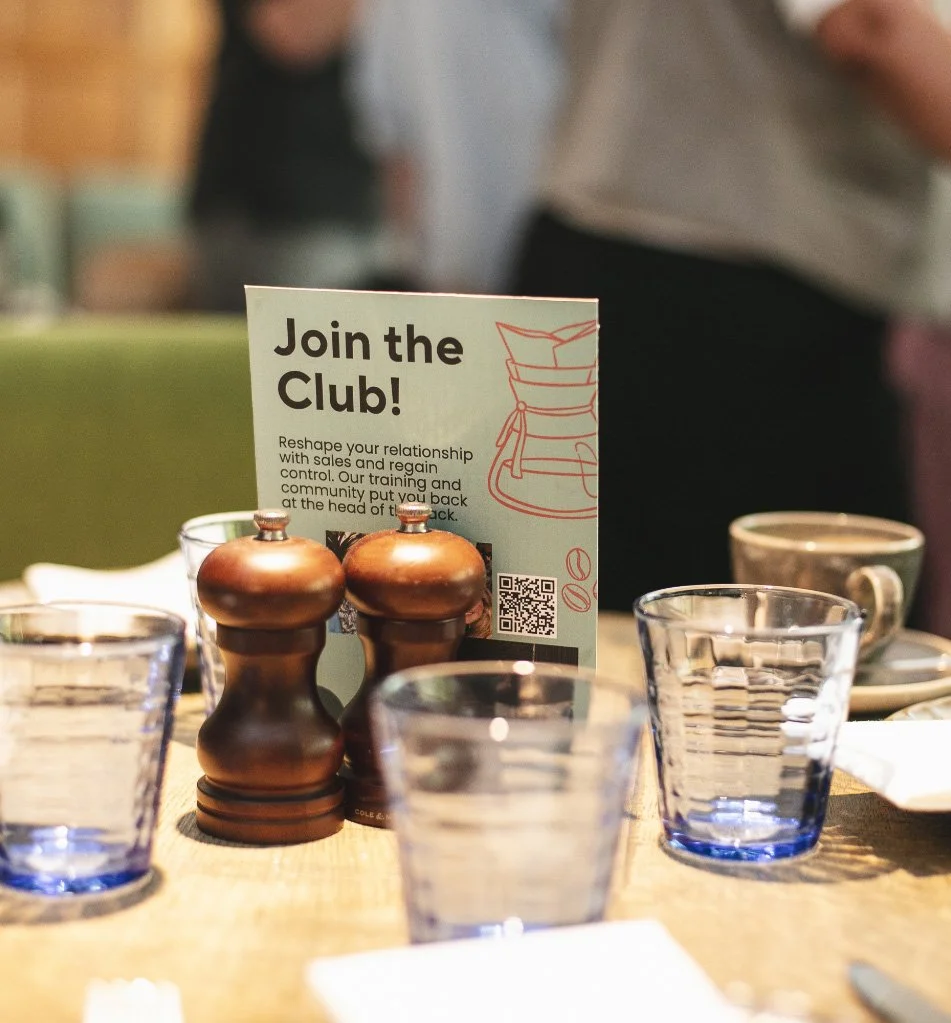Join the Club” flyer on a table with glasses and condiments