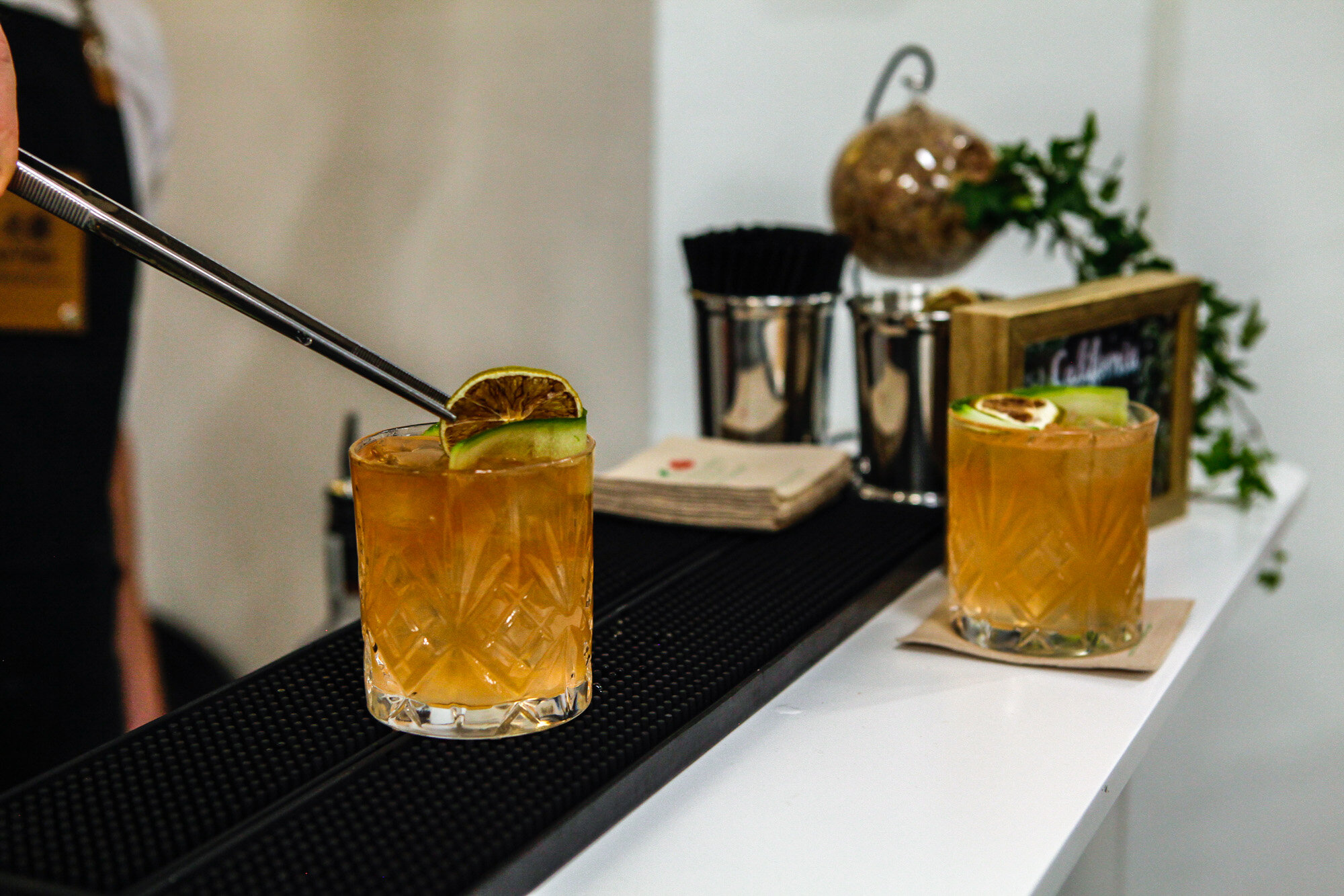Deux cocktails orange dans des verres décorés de tranches de citron et de concombre, sur un comptoir de bar