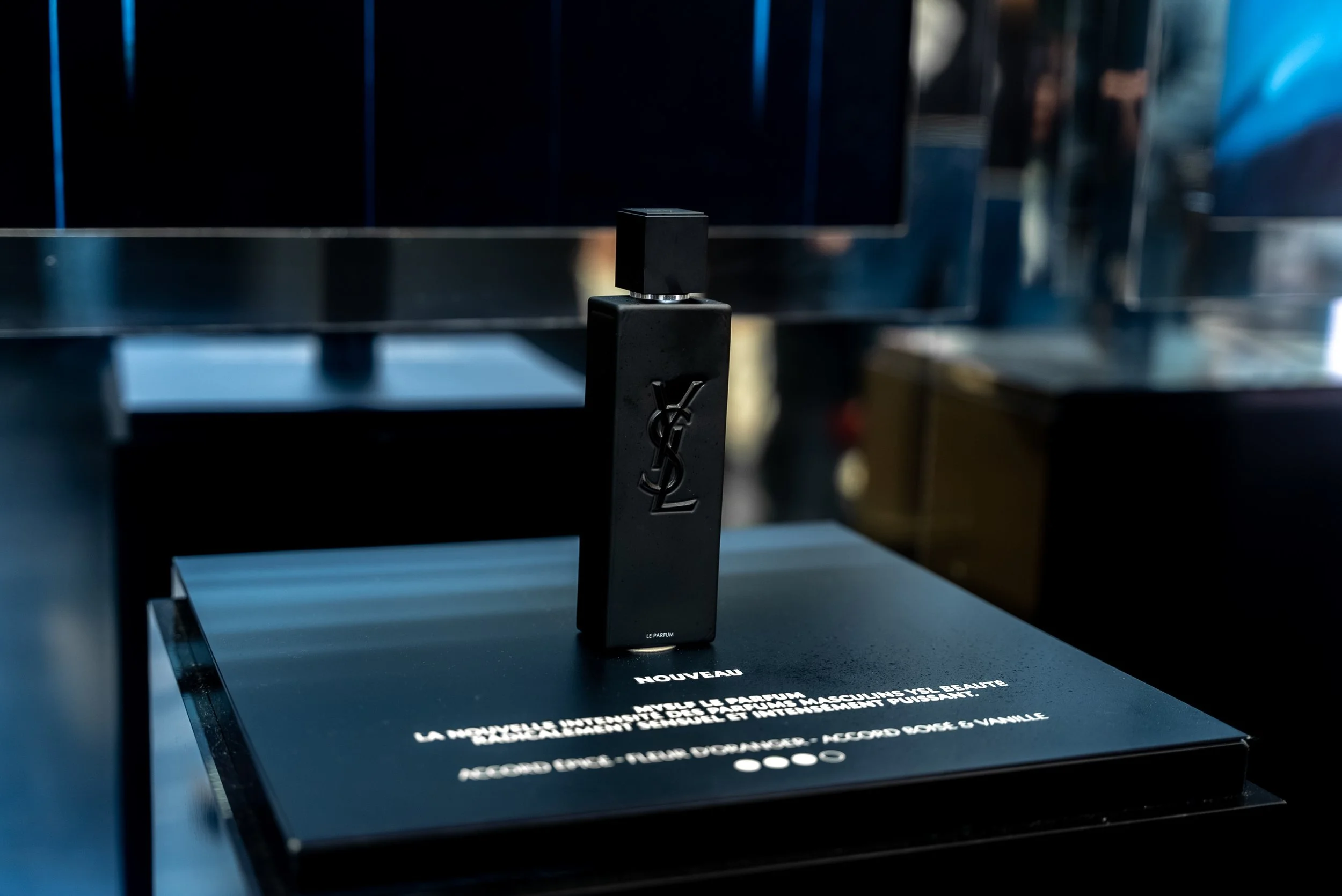 Une bouteille de parfum Yves Saint Laurent sur un socle noir avec des inscriptions en français et en anglais.