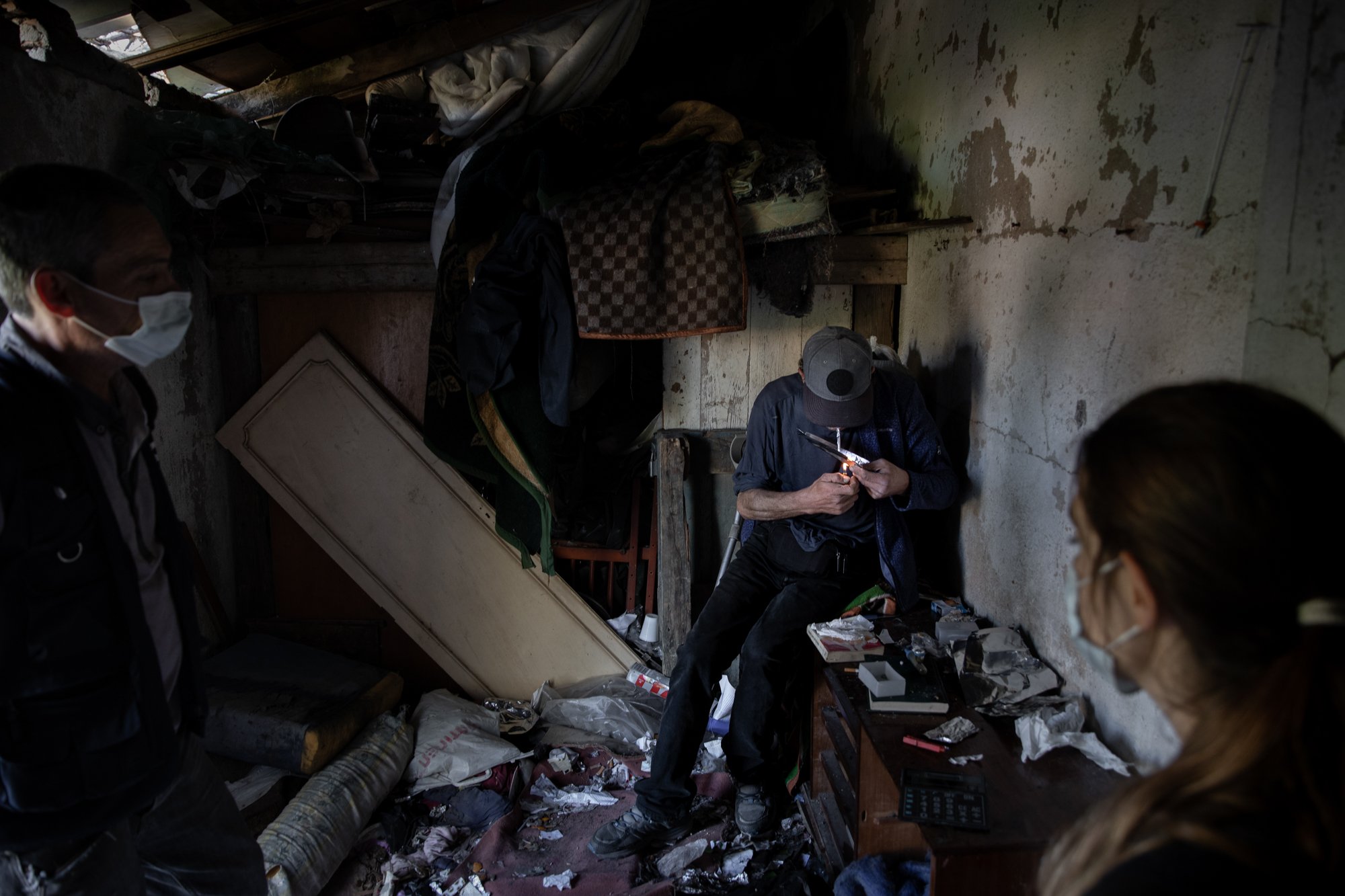  Two outreach workers, a psycologist (right) and a former addict (left) talk to Miguel as he smokes heroin at an abandoned house in Lumiar, Lisbon. 3/11/2020 