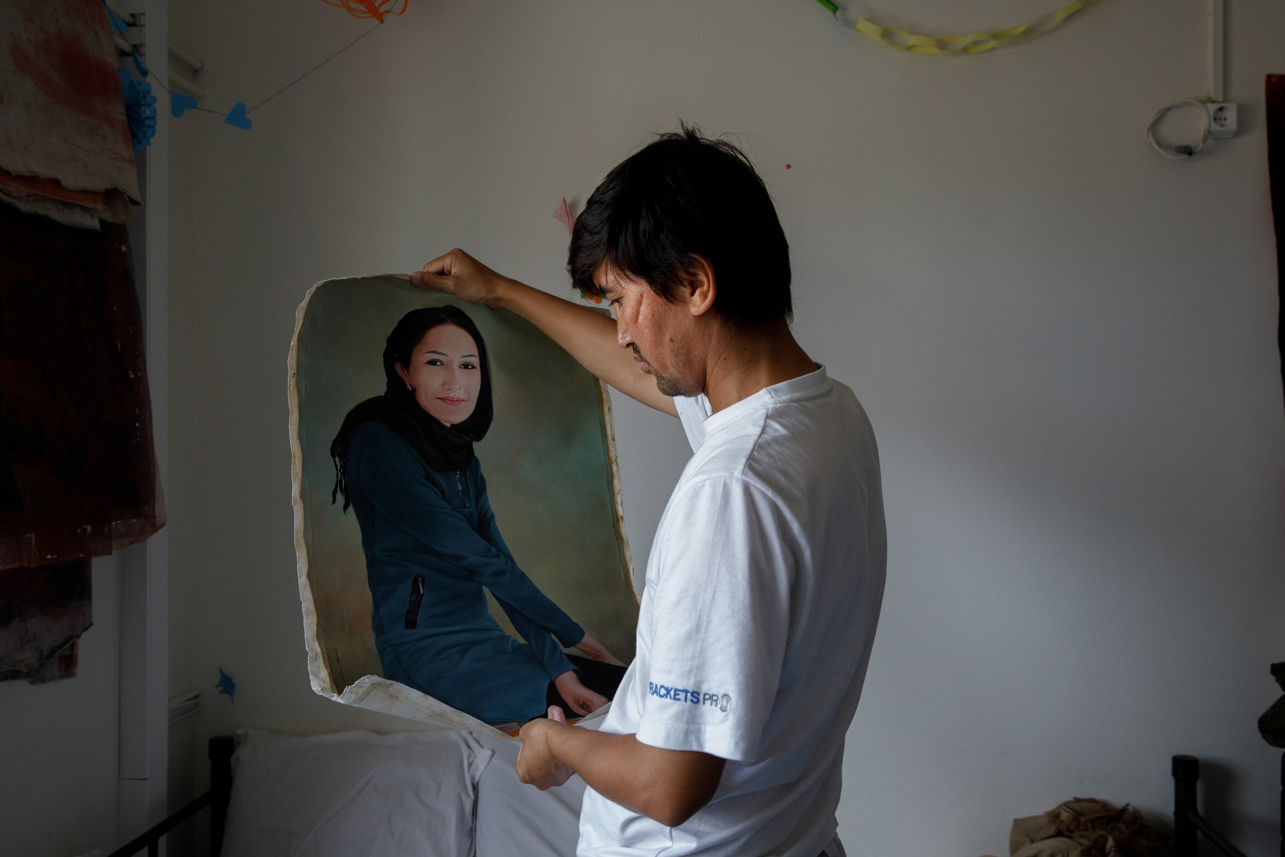  Juma Ahmadi holds up the a portrait of his wife, who stayed back in Afghanistan. Juma came with his two nieces, Farida, violinist, and Zhora, trumpet player, and left behind in Kabul his wife and his son, who at the time was one month old. June 2022