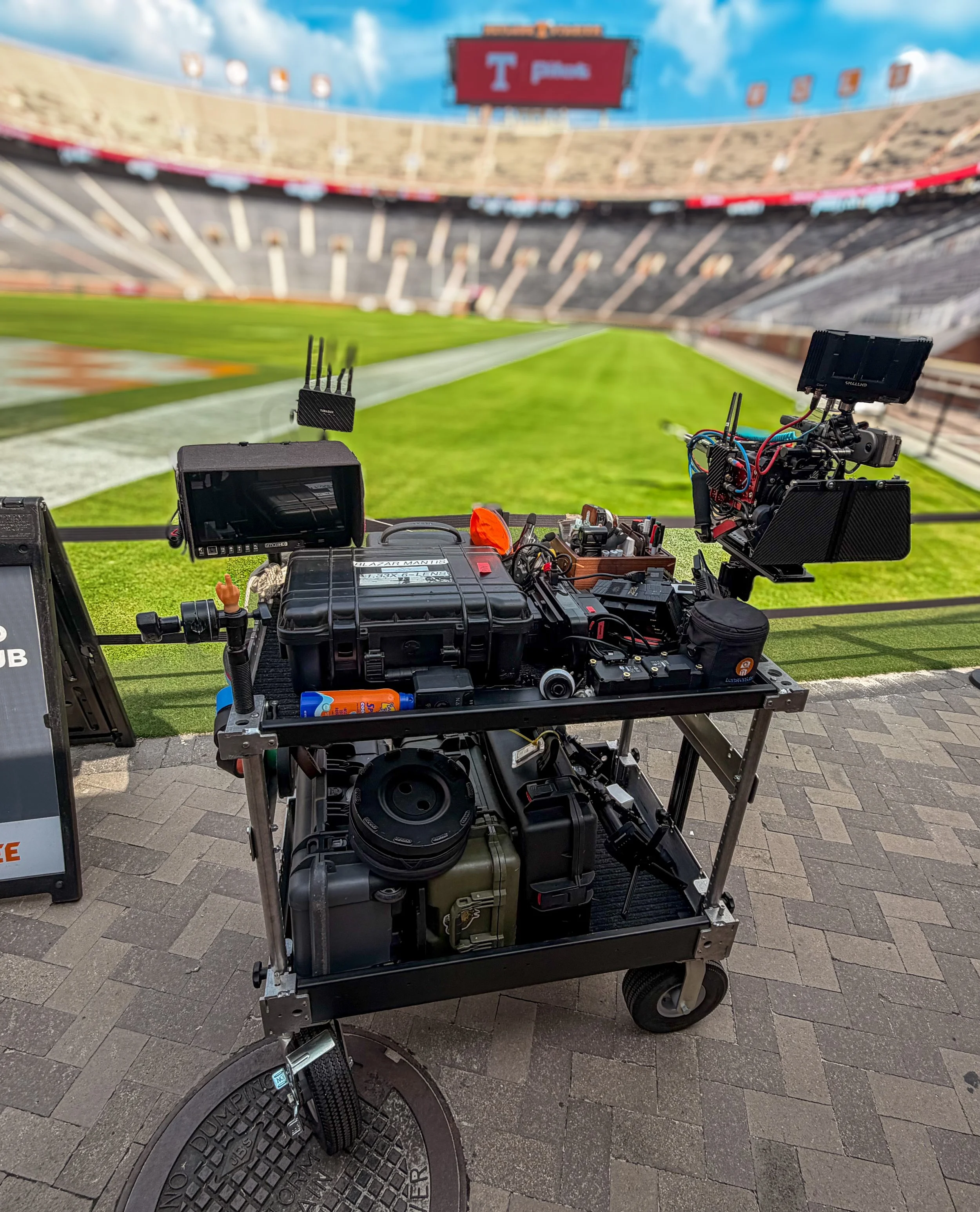 Camera equipment on a cart at a football stadium with empty seats and a digital scoreboard in the background. Neyland Stadium, Knoxville TN.