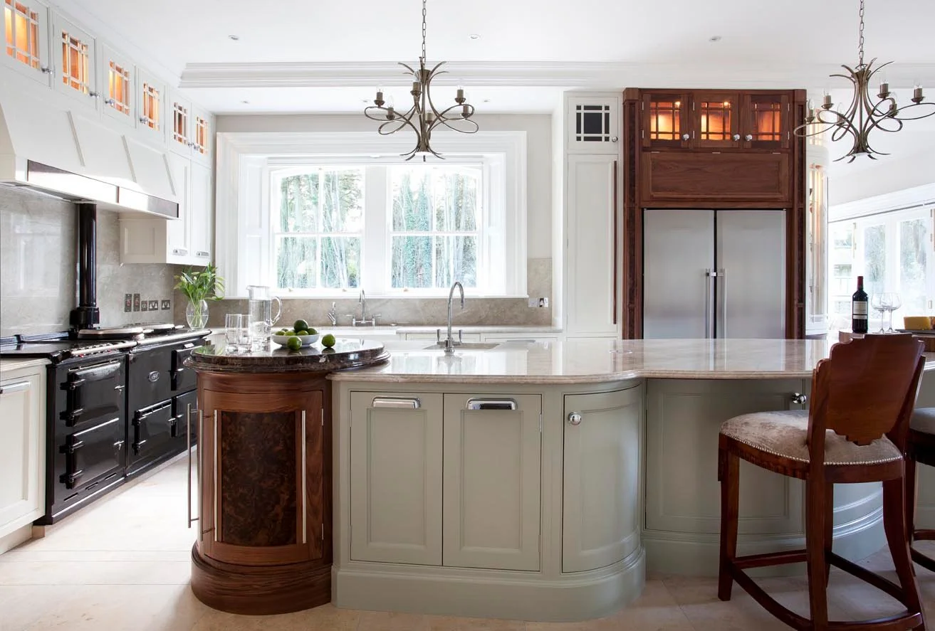 Completed kitchen with curved island, mixed cabinetry and architectural lighting.