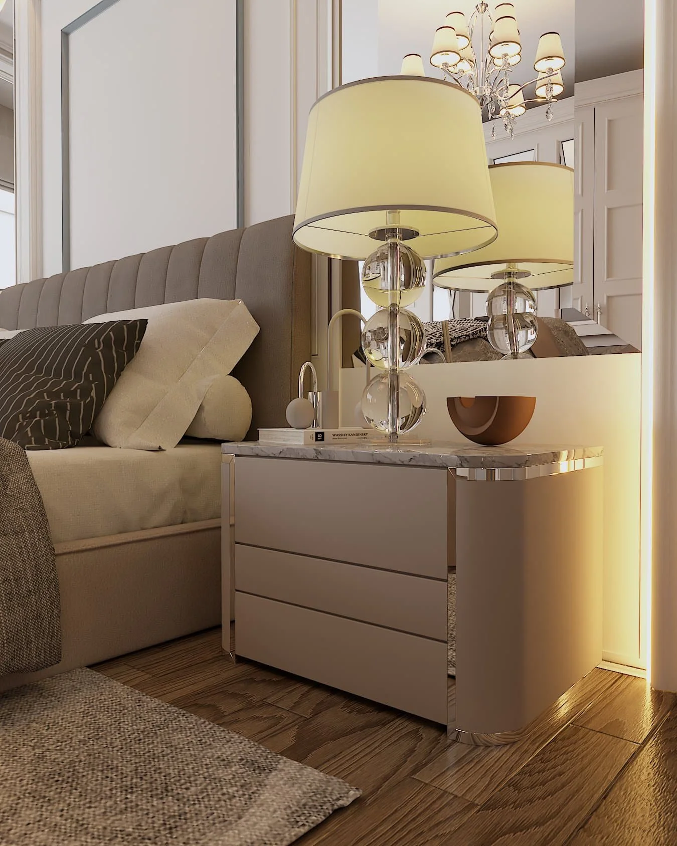 a close up of a grey bedside table with a wooden bowl, a book and a glass and metal light with a cream lampshade. the edge of the bed is to the left and a mirror is on the wall behind the bedside table