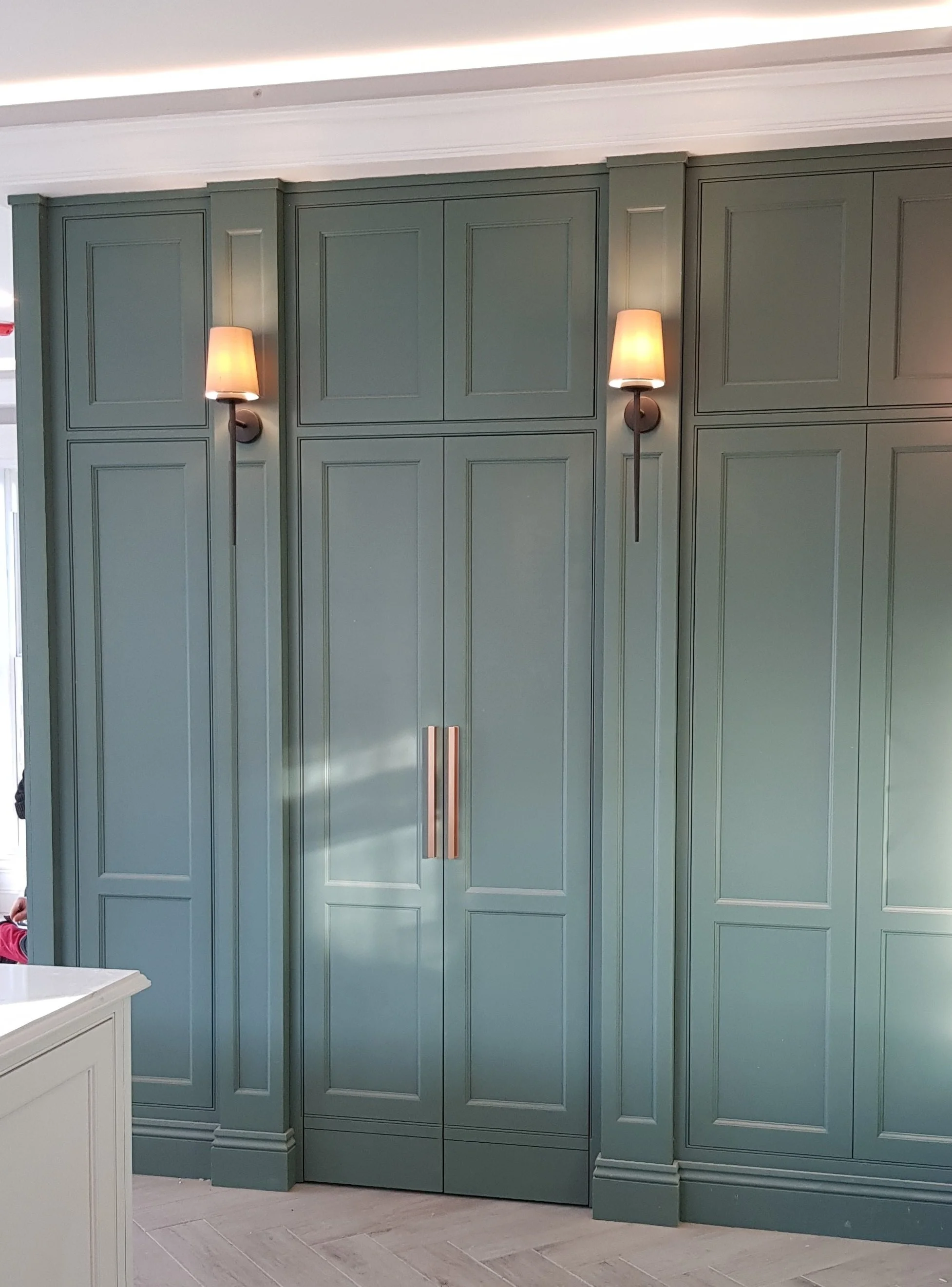 Completed kitchen with tall painted pantry cabinetry and brass handles.
