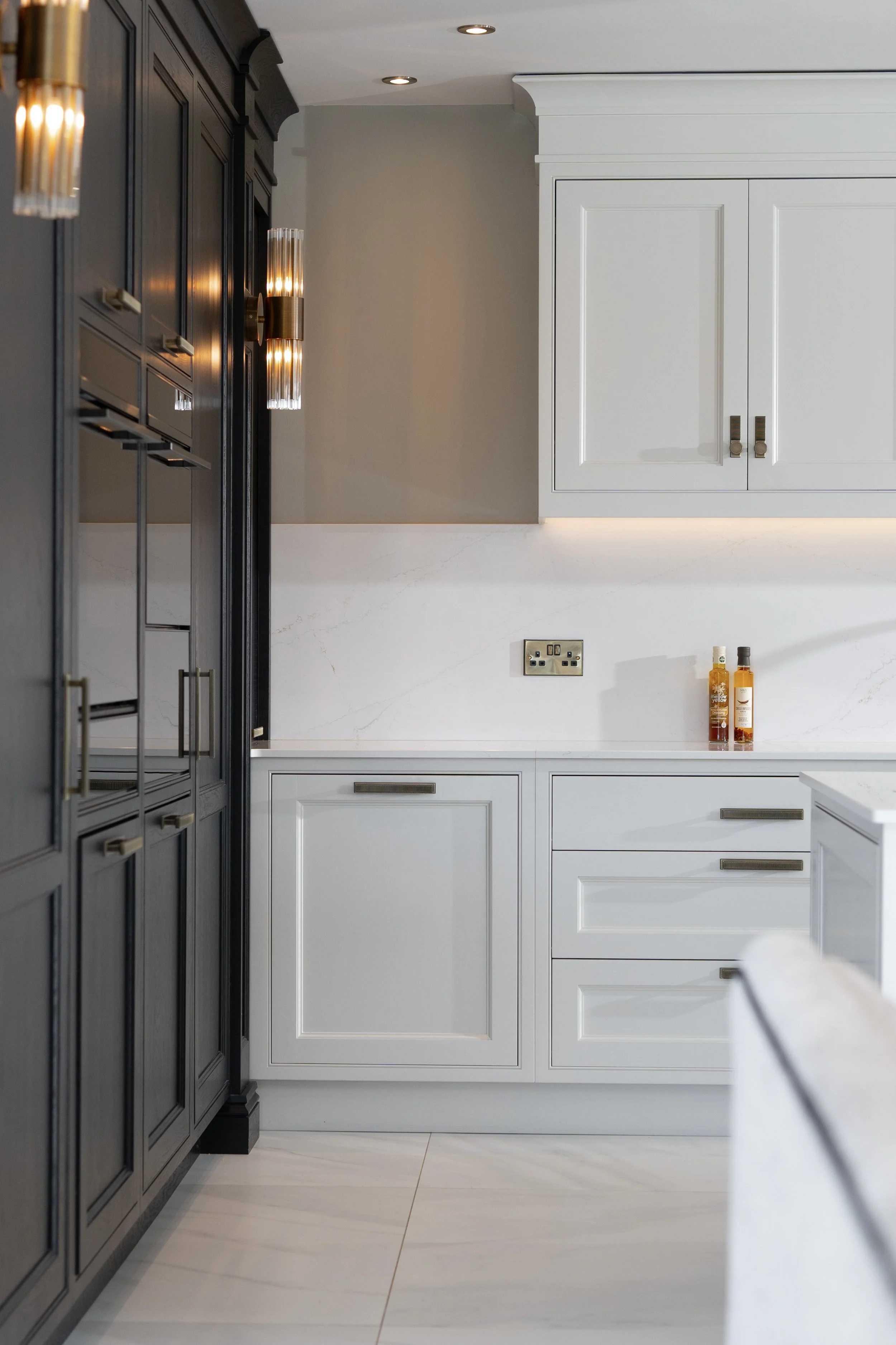 Luxury kitchen detail with contrasting dark and light cabinetry and integrated lighting.