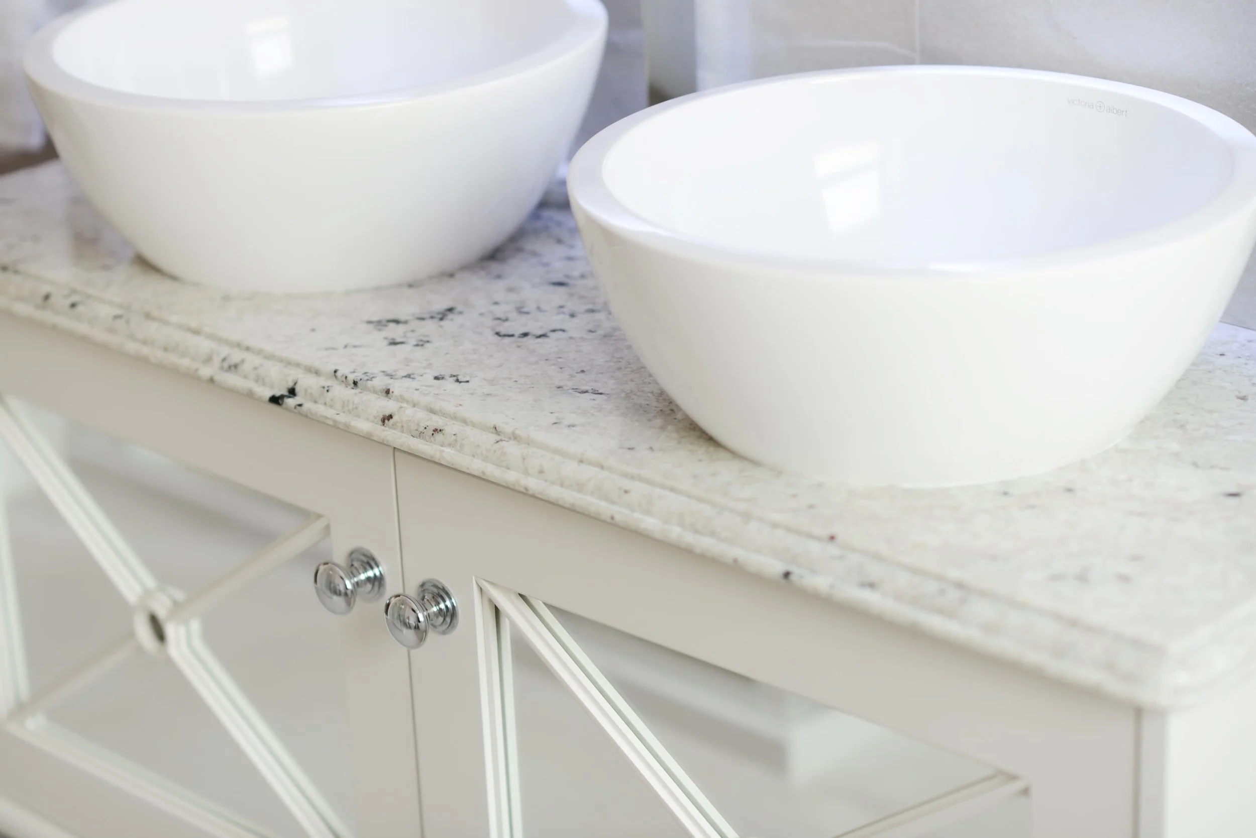 A white bathroom cabinet with white marble surface and two white sinks - Darren Morgan Design provides bespoke furniture in Ireland, UK and beyond