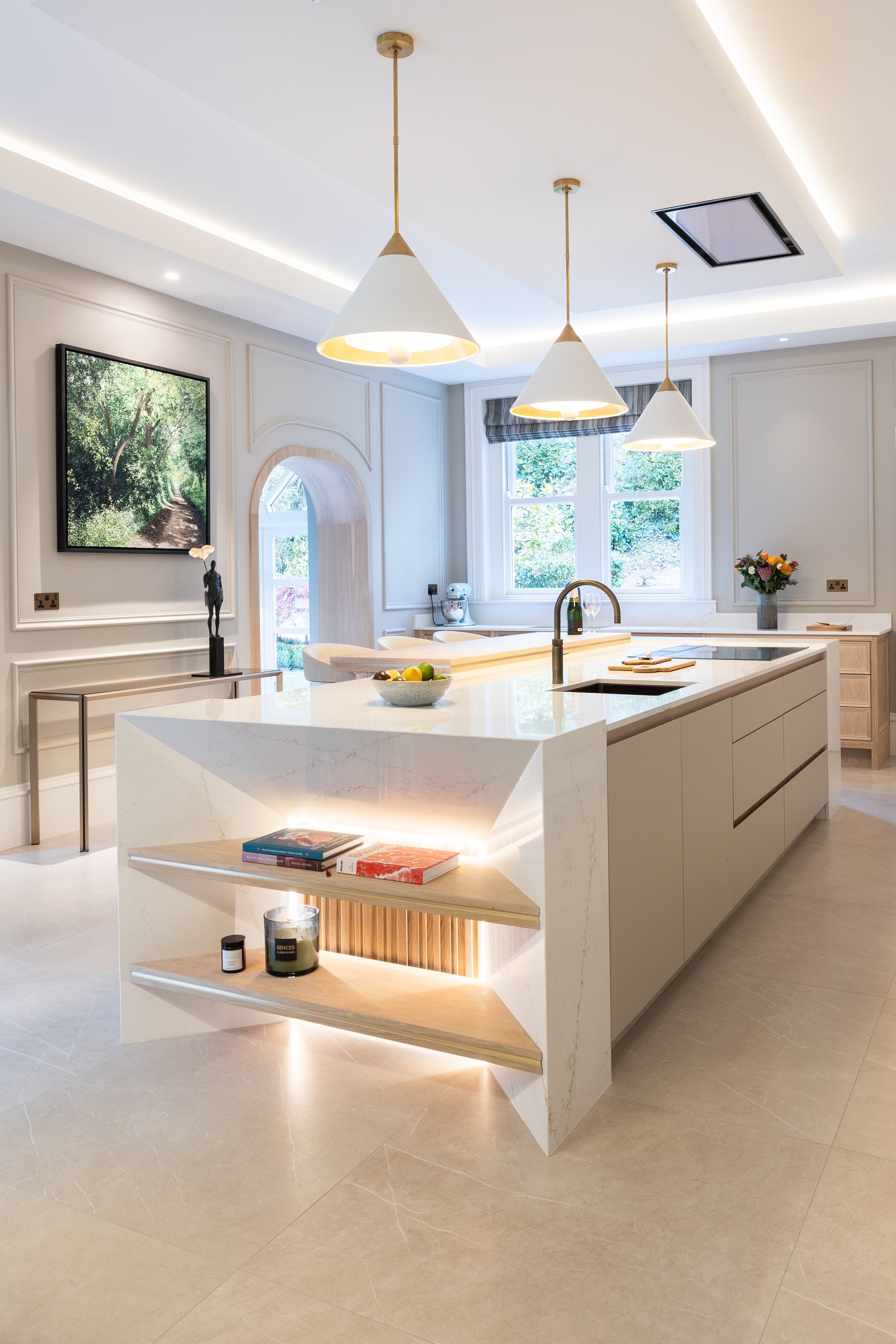 Luxury kitchen with pale cabinetry, island seating and pendant lighting.