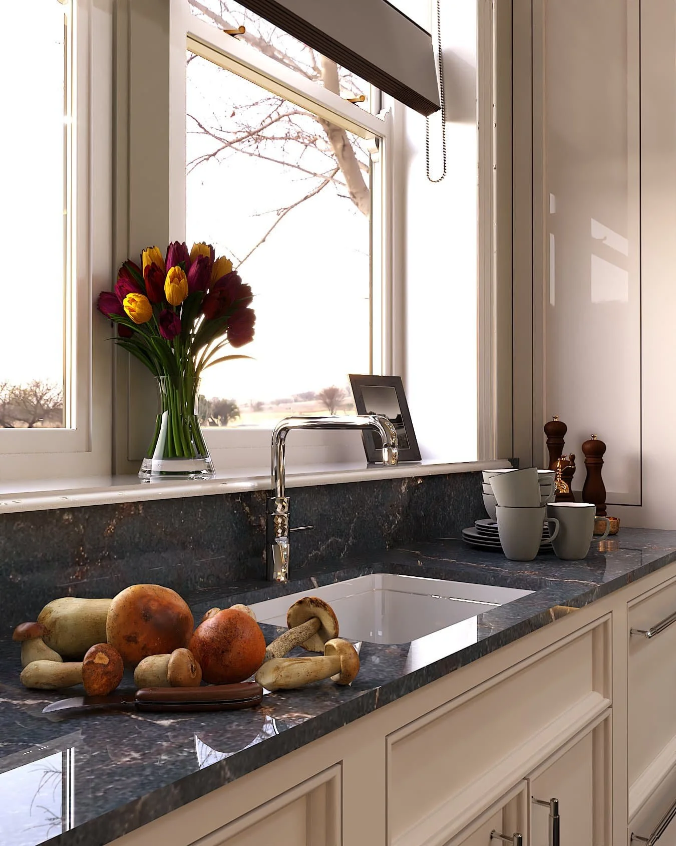 cream bespoke kitchen cabinets with black marble work surfaces and backsplash and a sing with a silver fitting. Flowers, vegetables and mugs are on the work surface that looks out a window