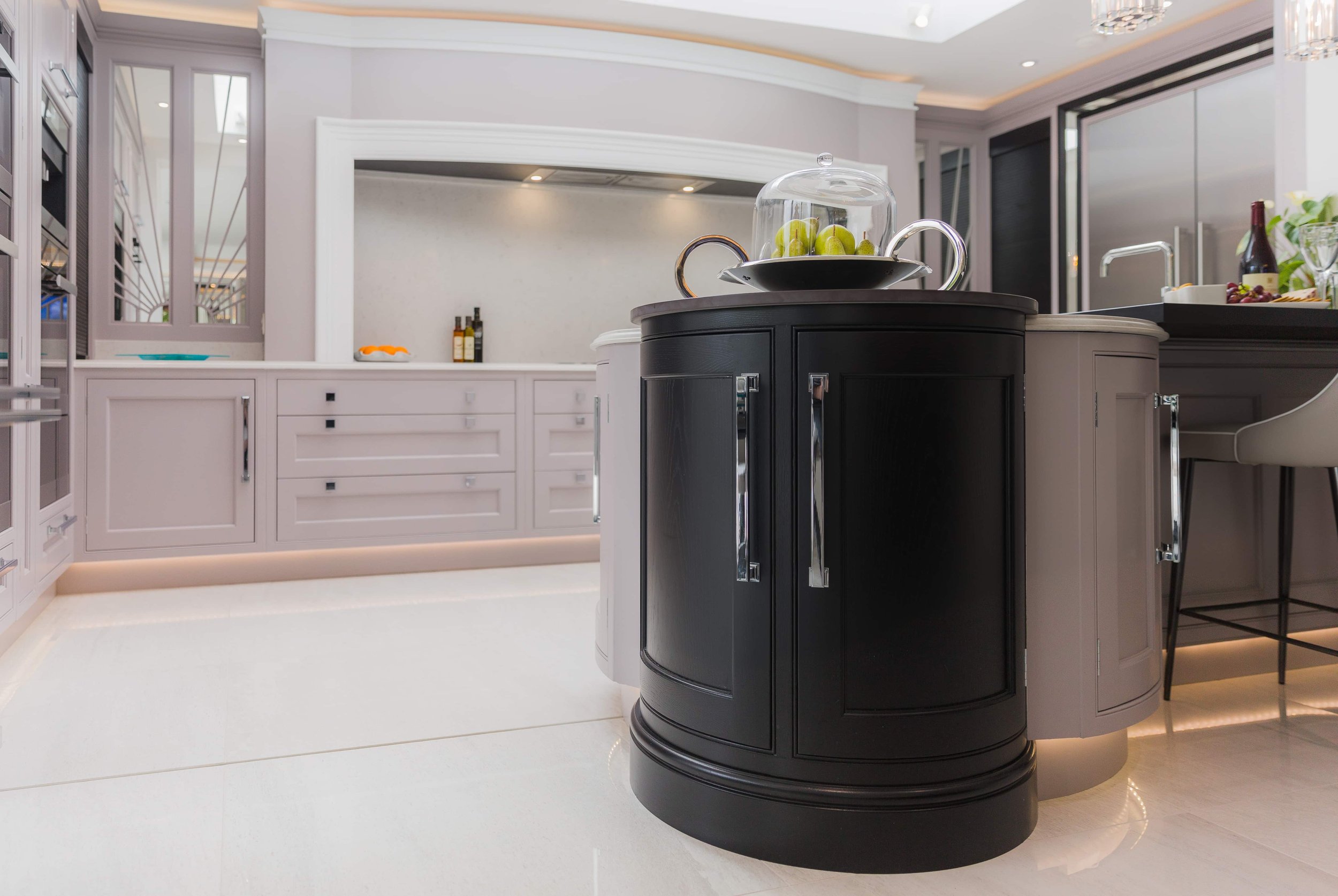 Completed contemporary kitchen featuring a curved dark island and bespoke cabinetry by Darren Morgan Design.